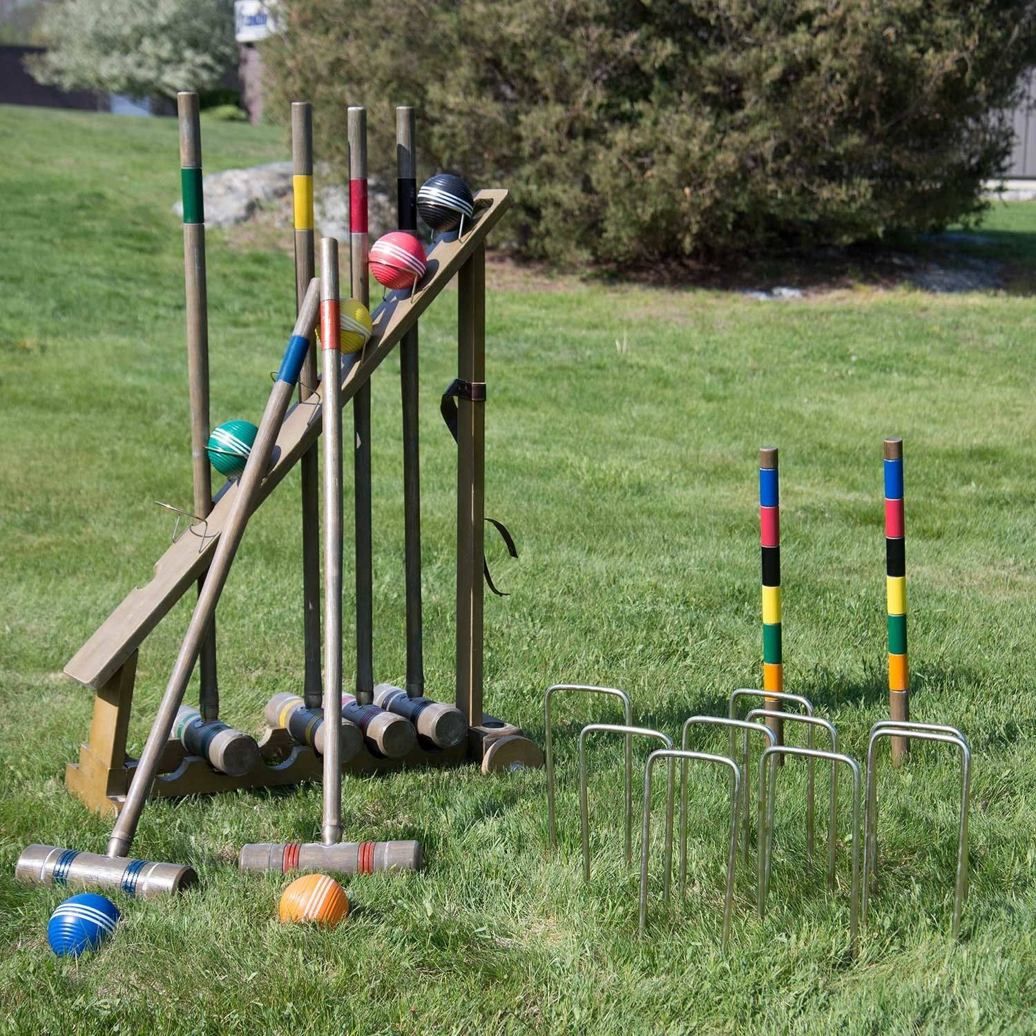 ball 桌布 壁紙 — 色彩繽紛的槌球裝備整齊地存放在陽光普照的草地後院的木架上。