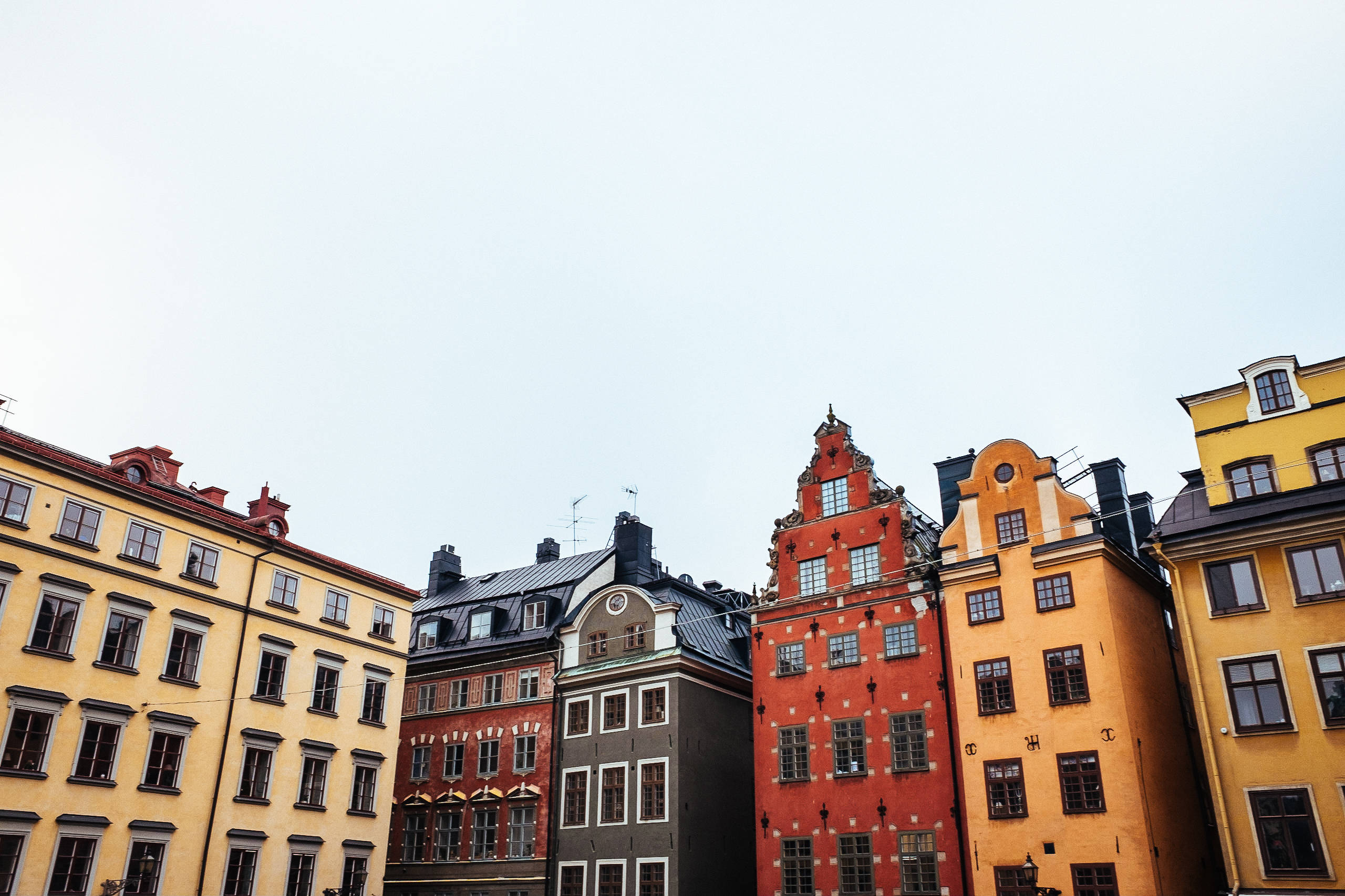 Sweden 桌布 壁紙 — 色彩繽紛的歷史建築，帶有華麗的山牆，在歐洲城市景觀中聳立在蒼白的天空下。