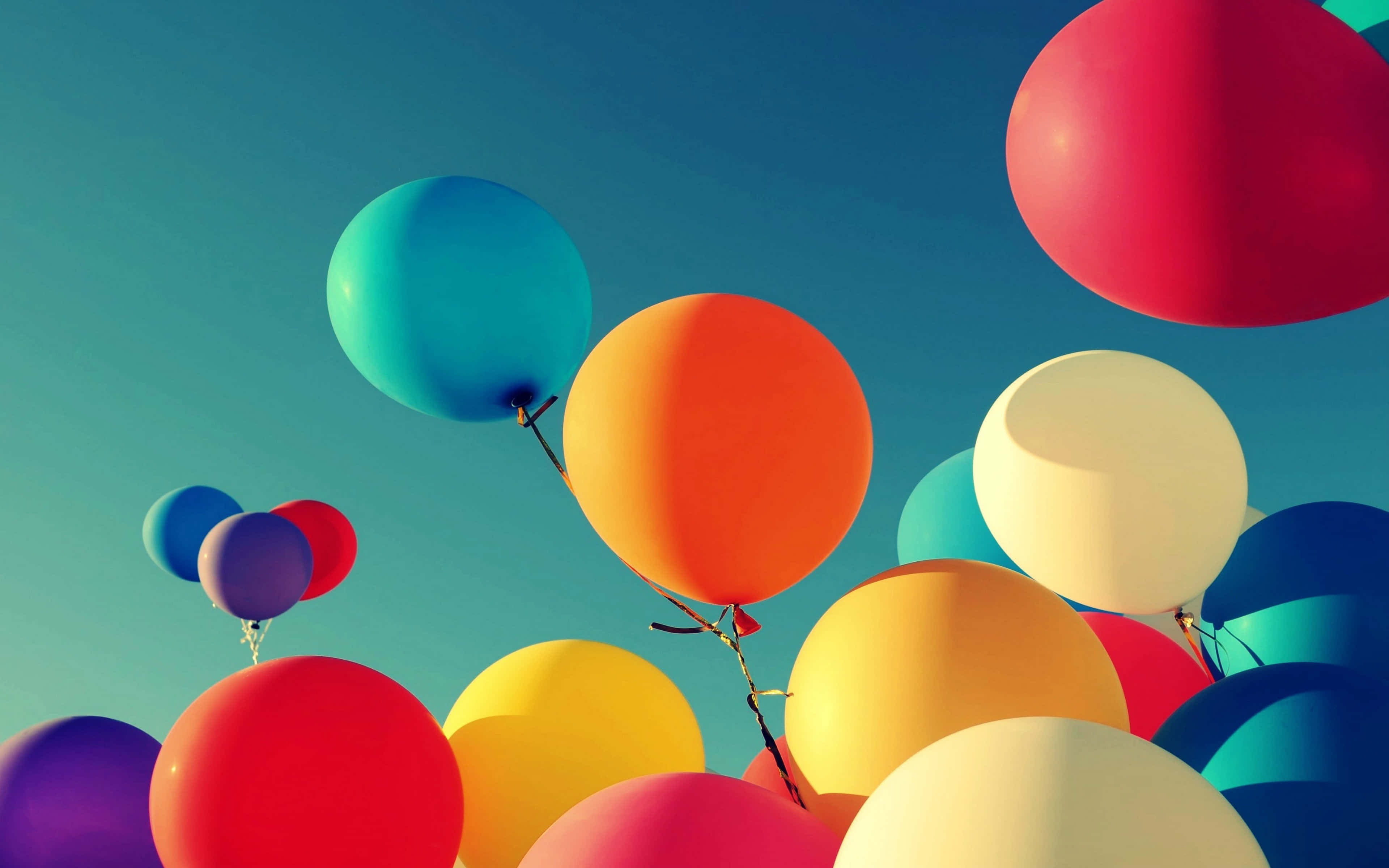 Balloons 桌布 壁紙 — 色彩繽紛的氣球在晴朗的藍天中飄浮，營造出歡樂的慶祝場景。