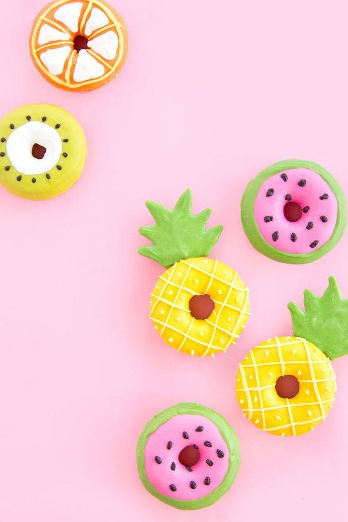cute girly phone 桌布 壁紙 — 色彩繽紛的水果主題甜甜圈，造型為鳳梨、西瓜和奇異果，排列在柔和的粉紅色背景上。
