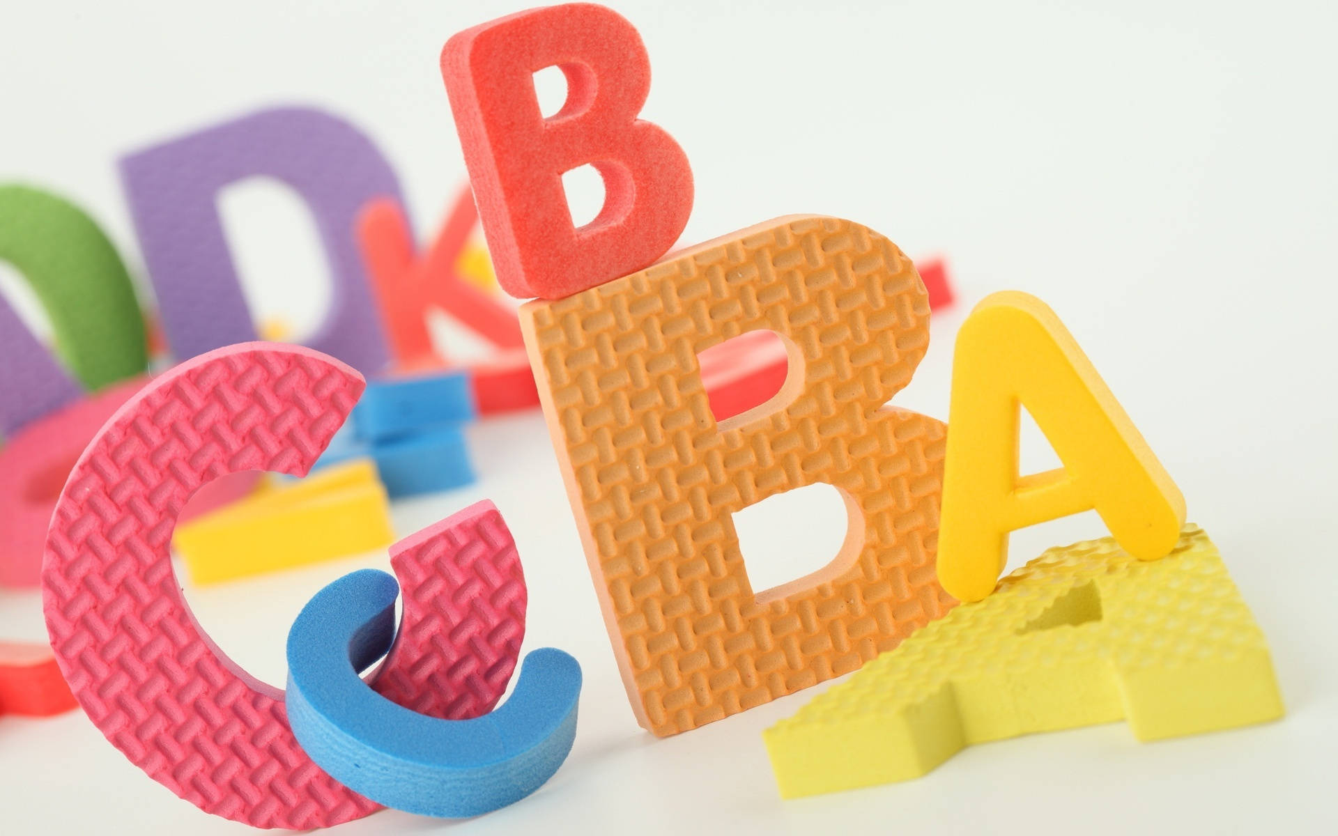Abc 桌布 壁紙 — 色彩繽紛的泡棉字母ABC以俏皮的方式堆疊在乾淨的白色背景上。