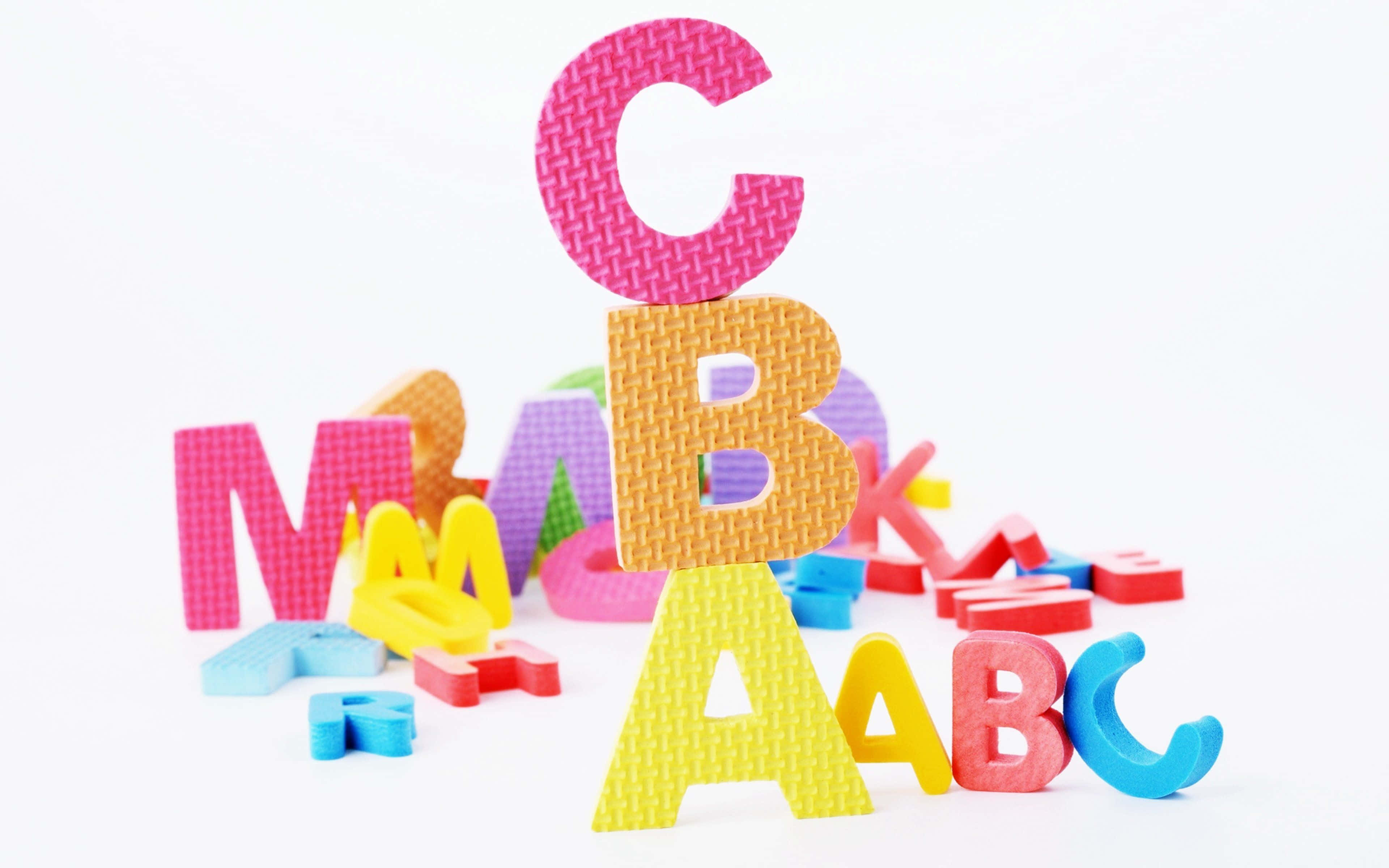 abc 桌布 壁紙 — 色彩繽紛的泡棉字母散落在白色背景上，A B C 直立堆疊。