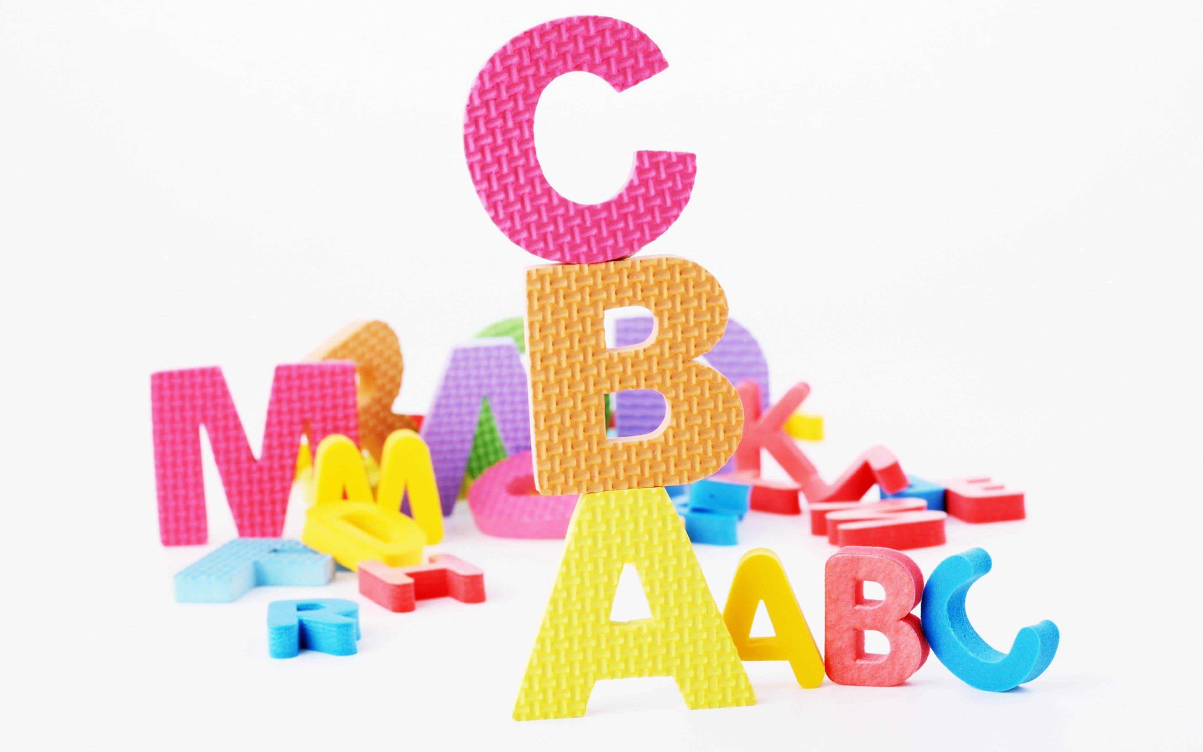 abc 桌布 壁紙 — 色彩繽紛的泡棉字母積木堆疊成一個有趣的塔，背景是乾淨的白色。