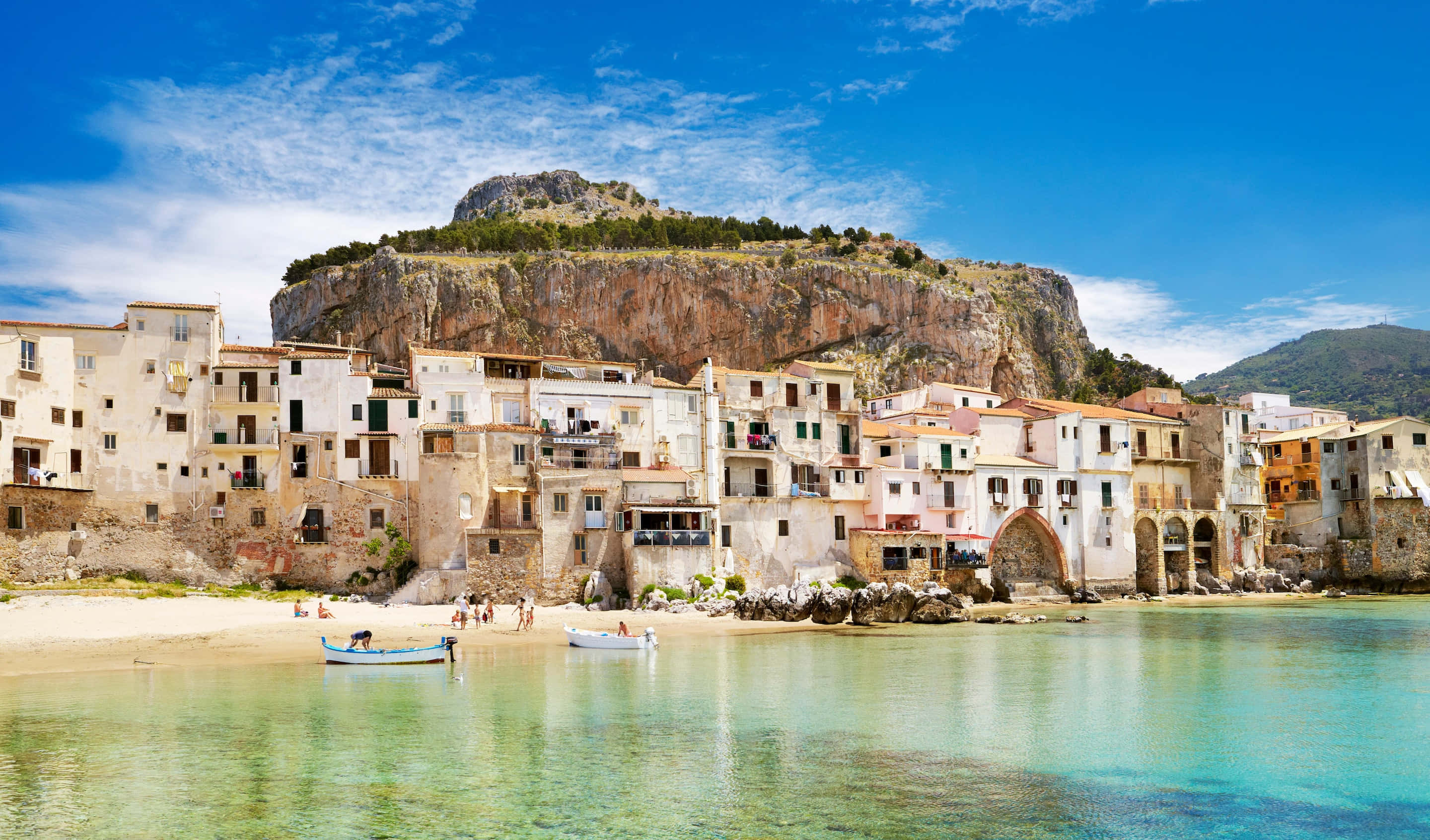 Italian Beach 桌布 壁紙 — 色彩繽紛的海岸村莊依附在岩石峭壁上，下方是碧綠的海水，上方是明亮的藍天。