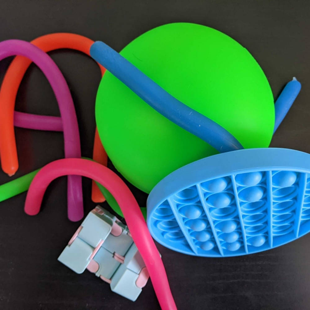Fidget Toys 桌布 壁紙 — 色彩繽紛的減壓玩具，包括一個綠色球、藍色彈力泡泡和彩色軟管，排列在深色表面上。