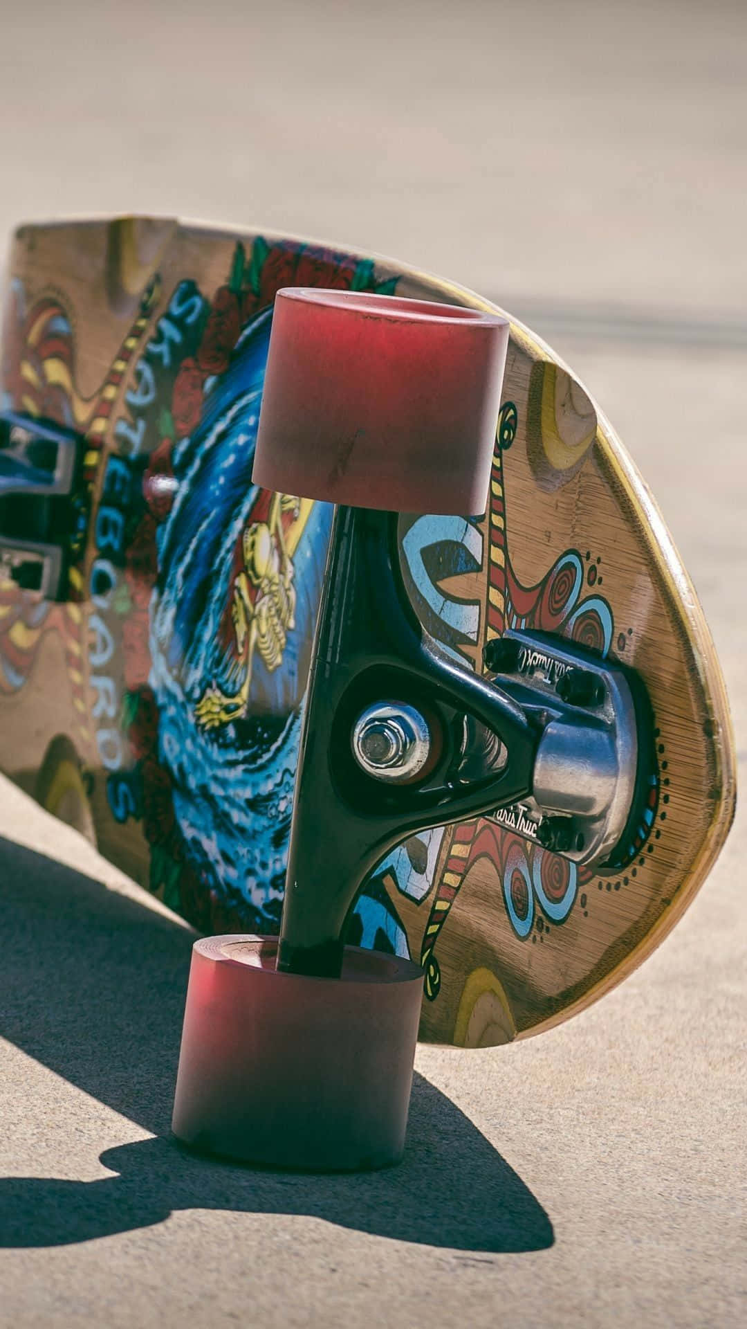 Skater Girl Aesthetic 桌布 壁紙 — 色彩繽紛的滑板特寫，紅色輪子擱在混凝土上，處於明亮陽光下。