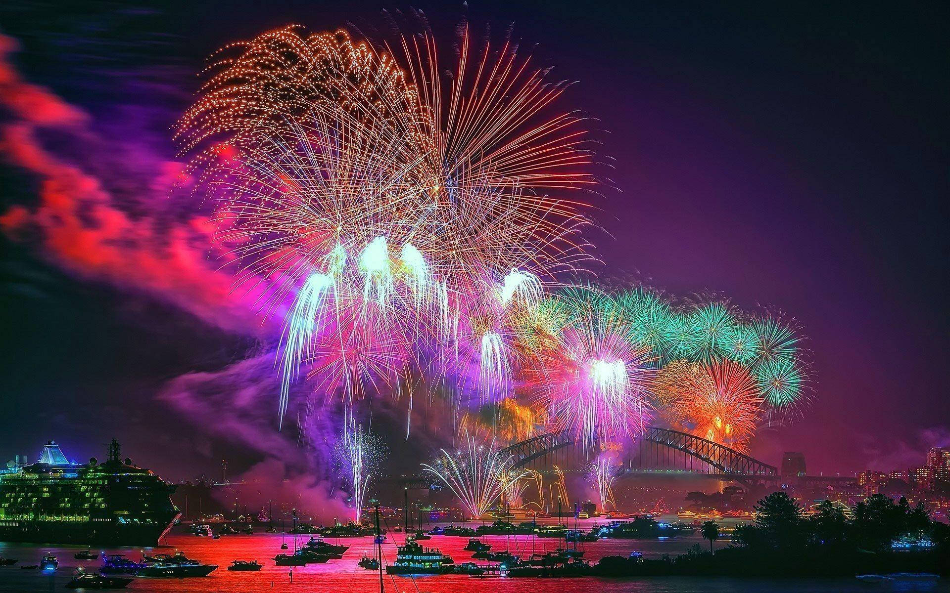 Fireworks 桌布 壁紙 — 色彩繽紛的煙火在夜間於雪梨港上空綻放，以耀眼色彩照亮標誌性大橋及水面。
