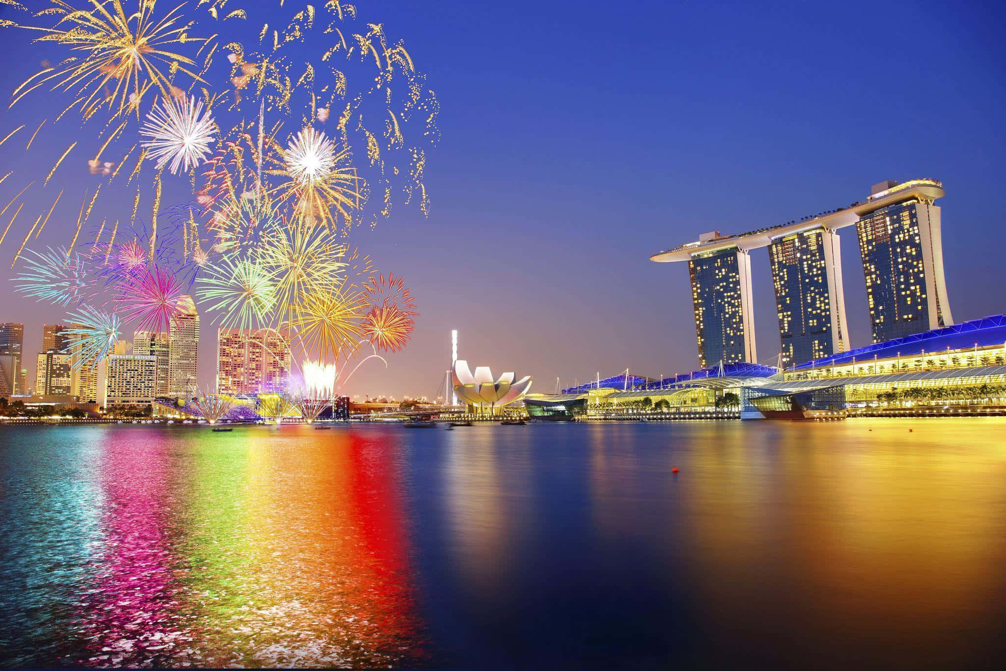 Singapore 桌布 壁紙 — 色彩繽紛的煙火在新加坡天際線上綻放，倒映在下方水面，濱海灣金沙塔在夜晚閃耀。