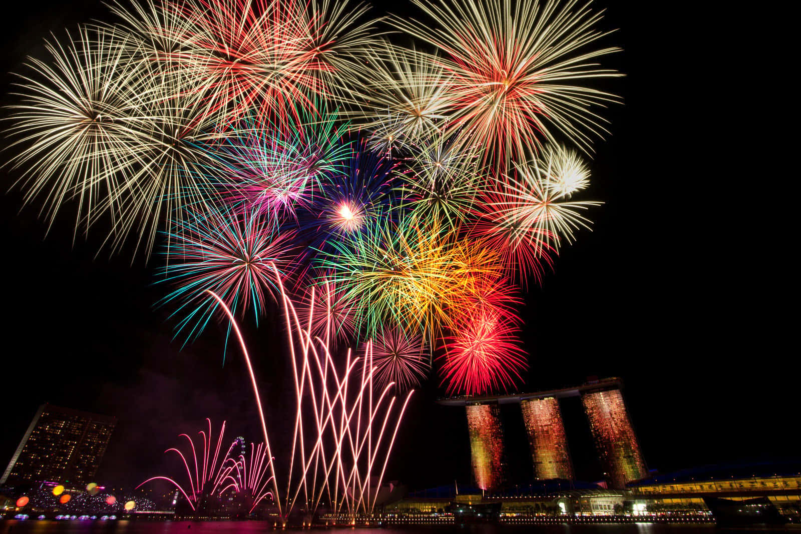 Celebration 桌布 壁紙 — 色彩繽紛的煙火在新加坡標誌性的濱海灣金沙上空綻放，耀眼奪目。