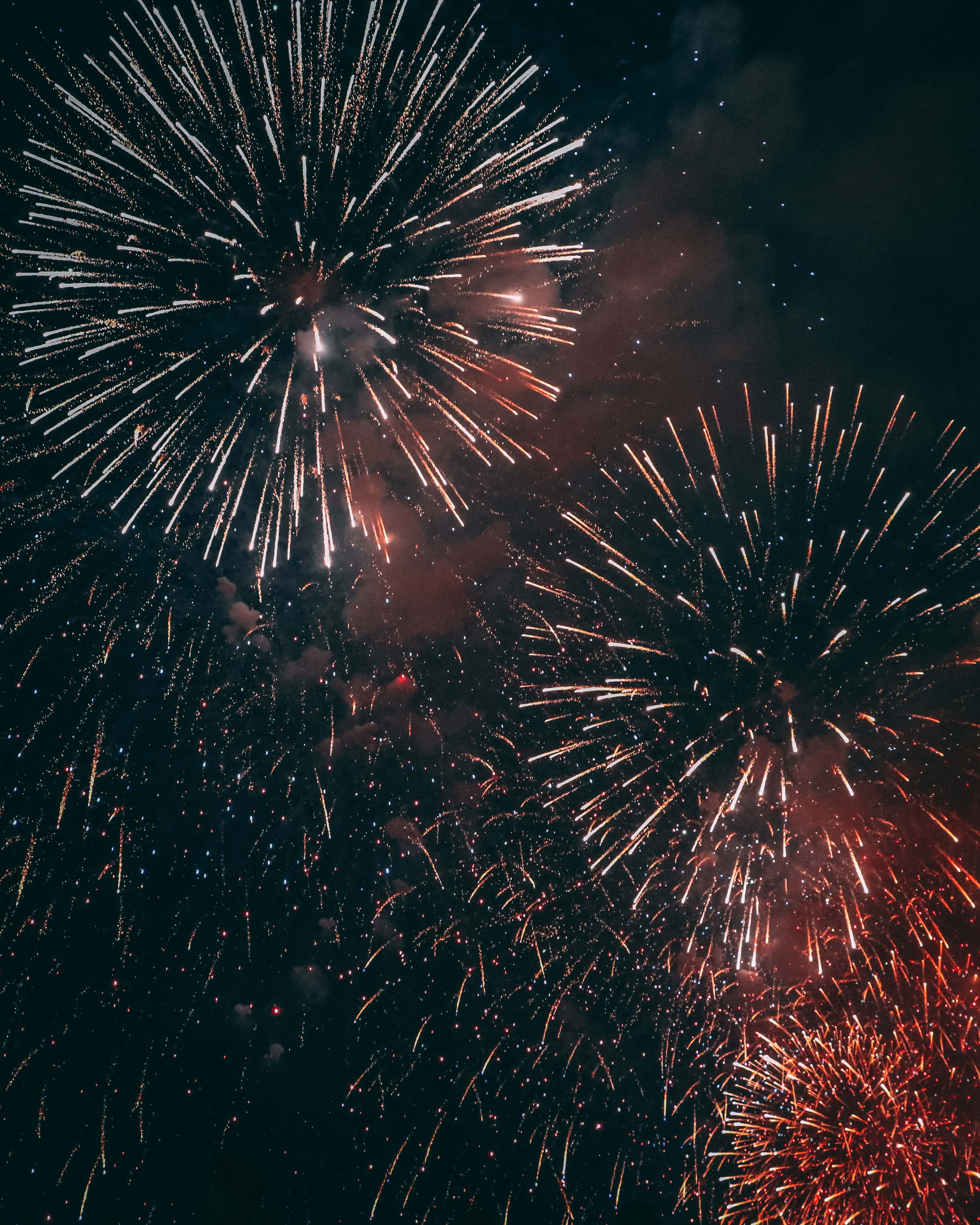 Fireworks 桌布 壁紙 — 色彩繽紛的煙火在繁星點點的夜空中綻放出耀眼的白光和橙光。