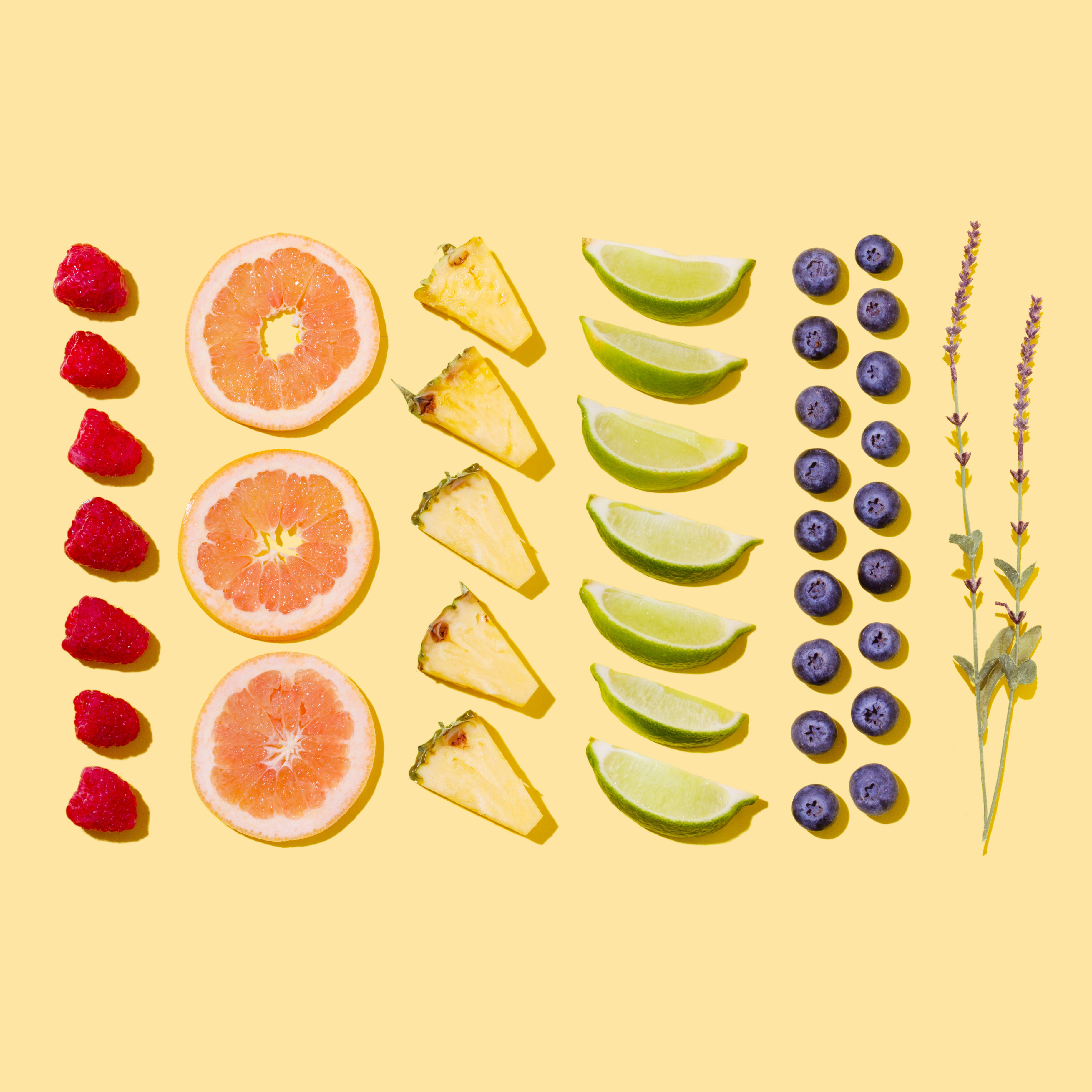 Fruit 桌布 壁紙 — 色彩繽紛的熱帶水果和莓果整齊地排列在陽光黃色背景上，搭配薰衣草枝。
