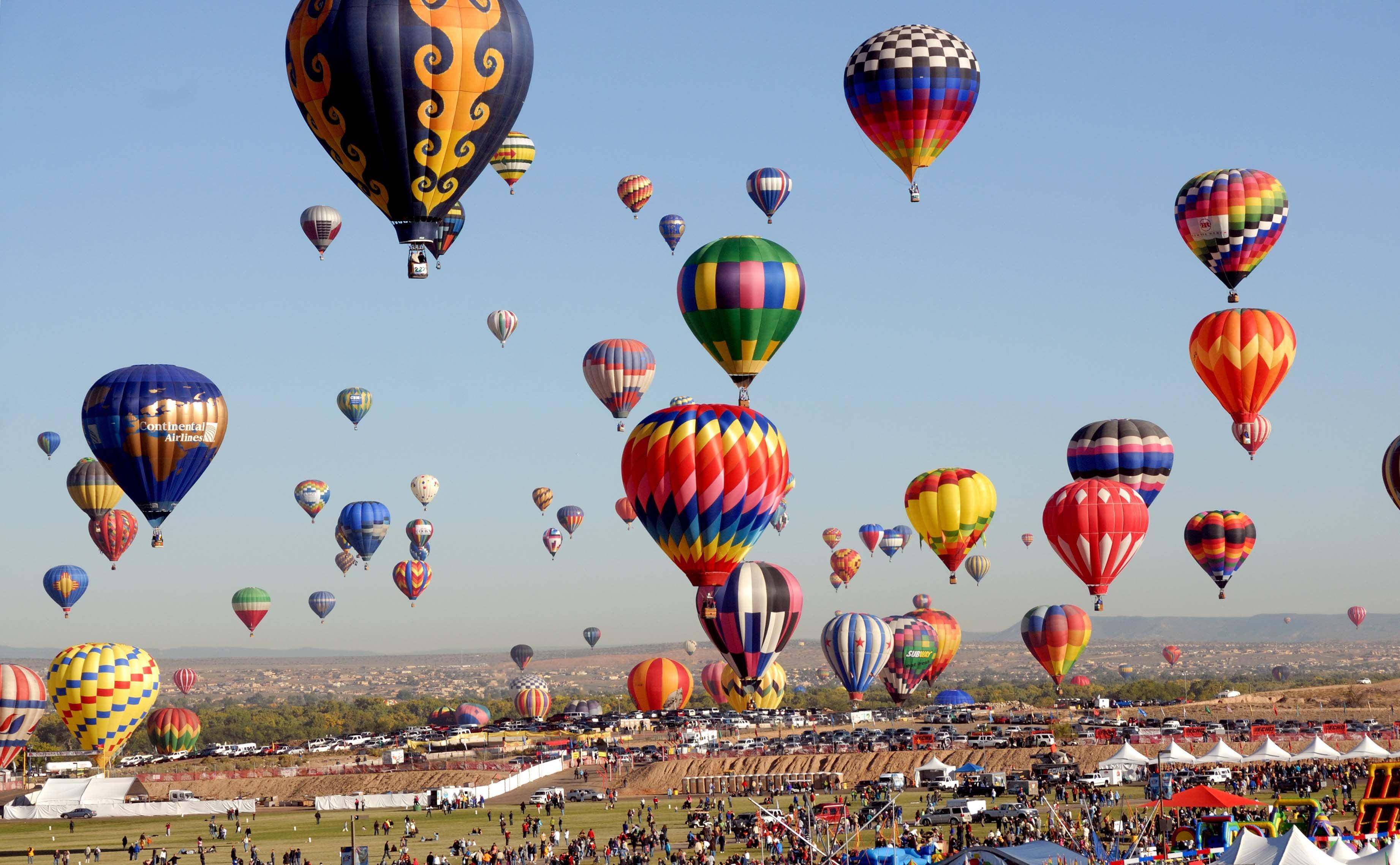 Balloon 桌布 壁紙 — 色彩繽紛的熱氣球以耀眼的圖案在晴朗的藍天下翱翔於熱鬧的節日人群之上。