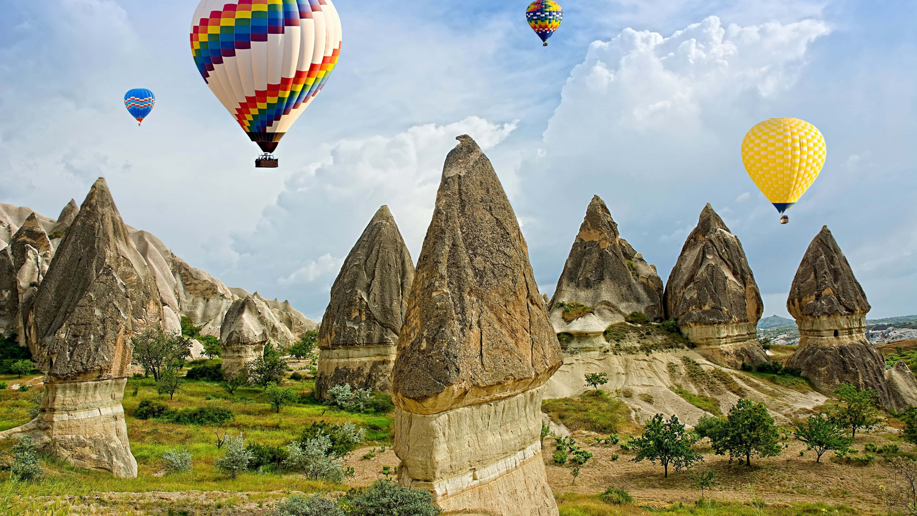 Hot Air Balloon 桌布 壁紙 — 色彩繽紛的熱氣球在卡帕多奇亞標誌性的精靈煙囪上空飄浮，天空部分多雲。