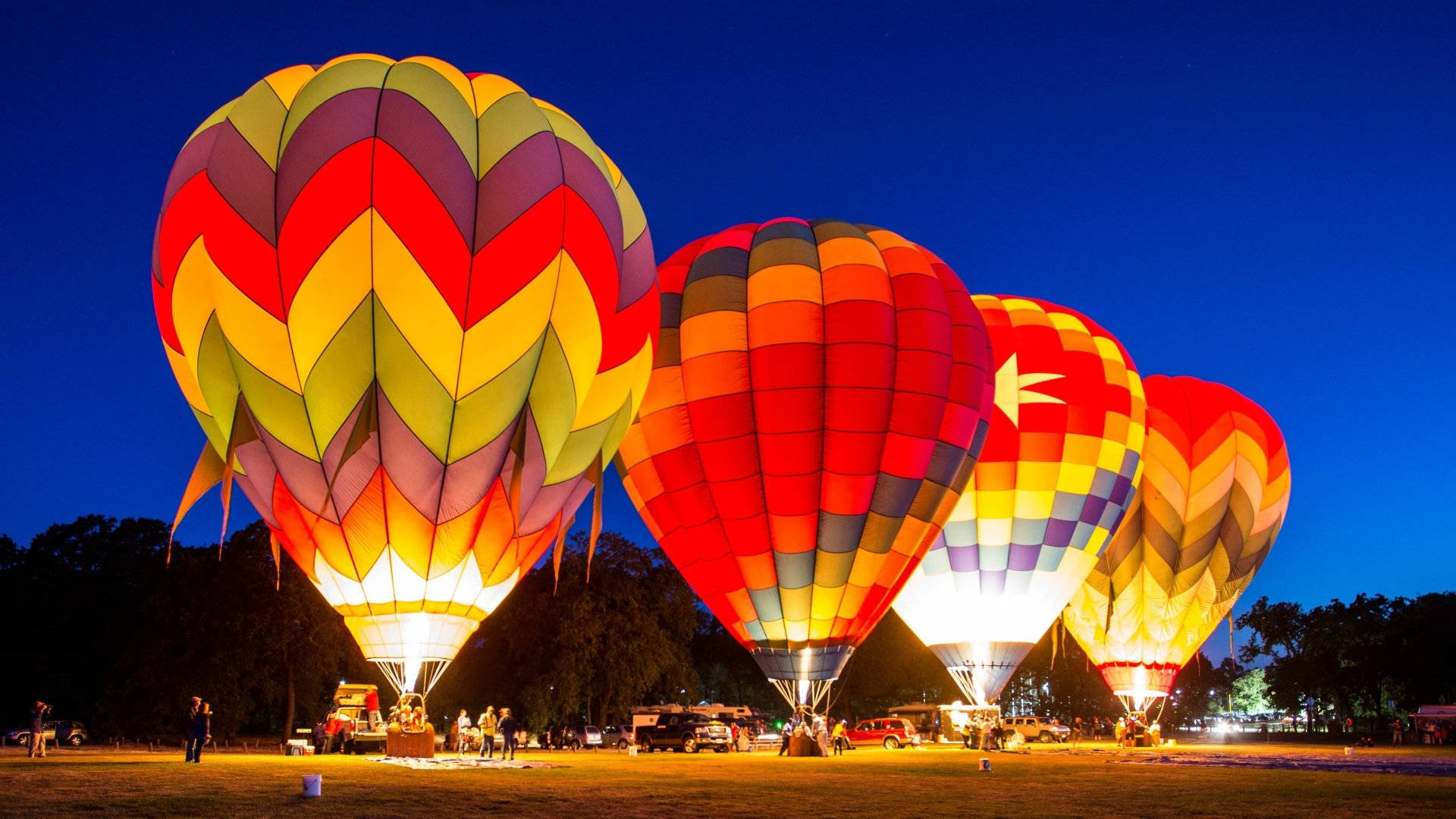Hot Air Balloon 桌布 壁紙 — 色彩繽紛的熱氣球在深藍色的暮色天空中散發溫暖的光芒，準備起飛。