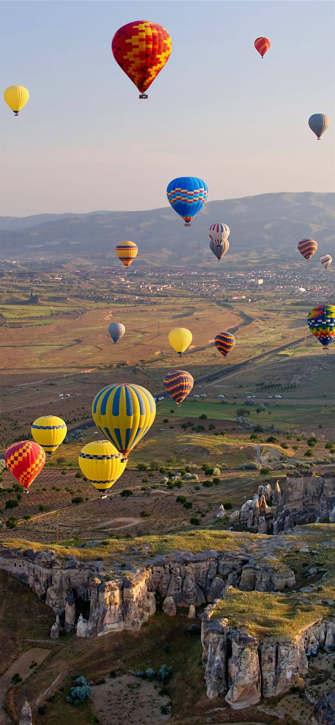 Cappadocia 桌布 壁紙 — 色彩繽紛的熱氣球在黃金時段飄過崎嶇的峽谷景觀。