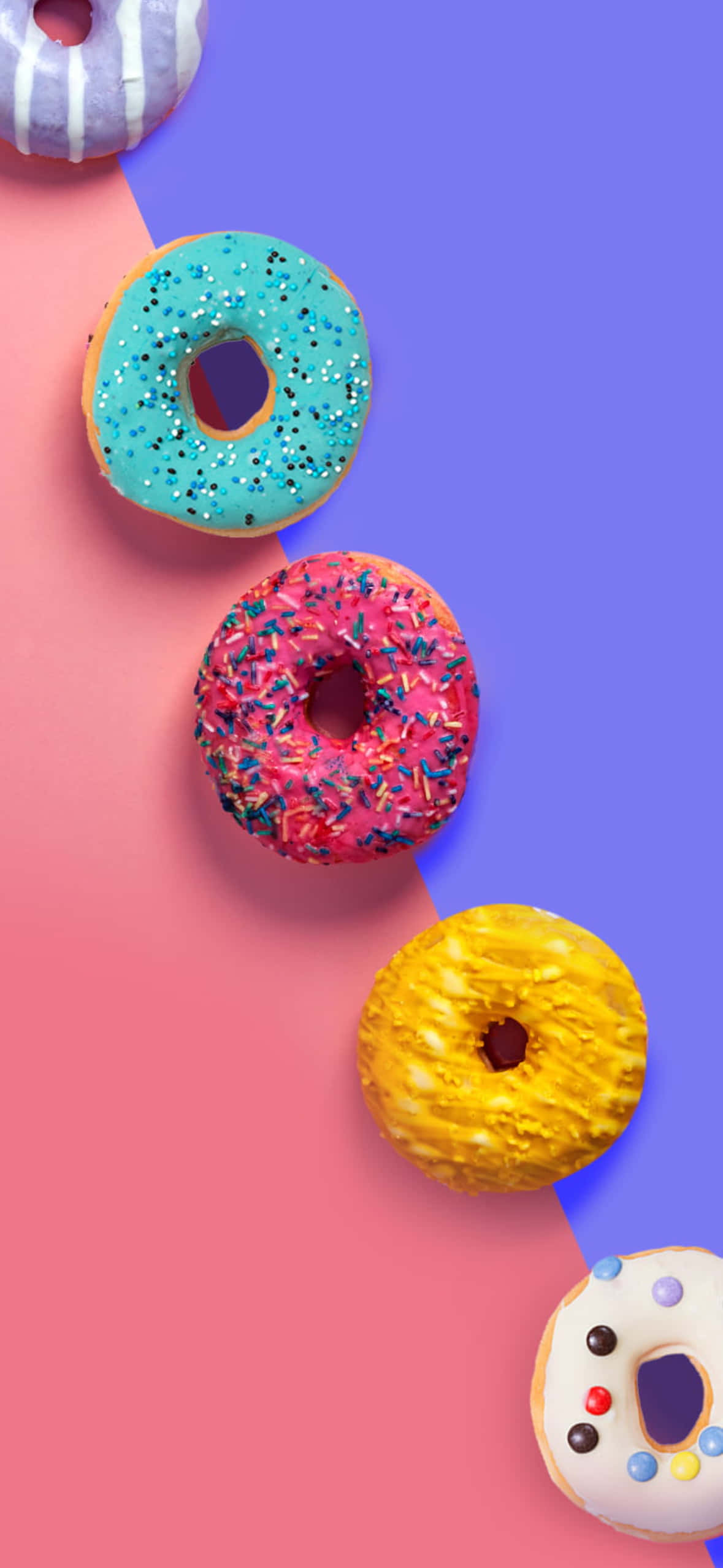 1179x2556 桌布 壁紙 — 色彩繽紛的甜甜圈，上面有彩色糖粒和糖霜，以對角線排列在鮮豔的粉紅色和紫色背景上。