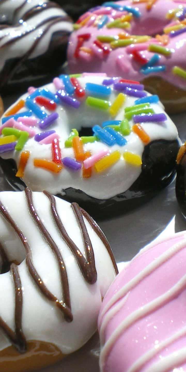 Pastry 桌布 壁紙 — 色彩繽紛的甜甜圈特寫，飾有彩虹糖針、巧克力淋醬和光澤糖霜。