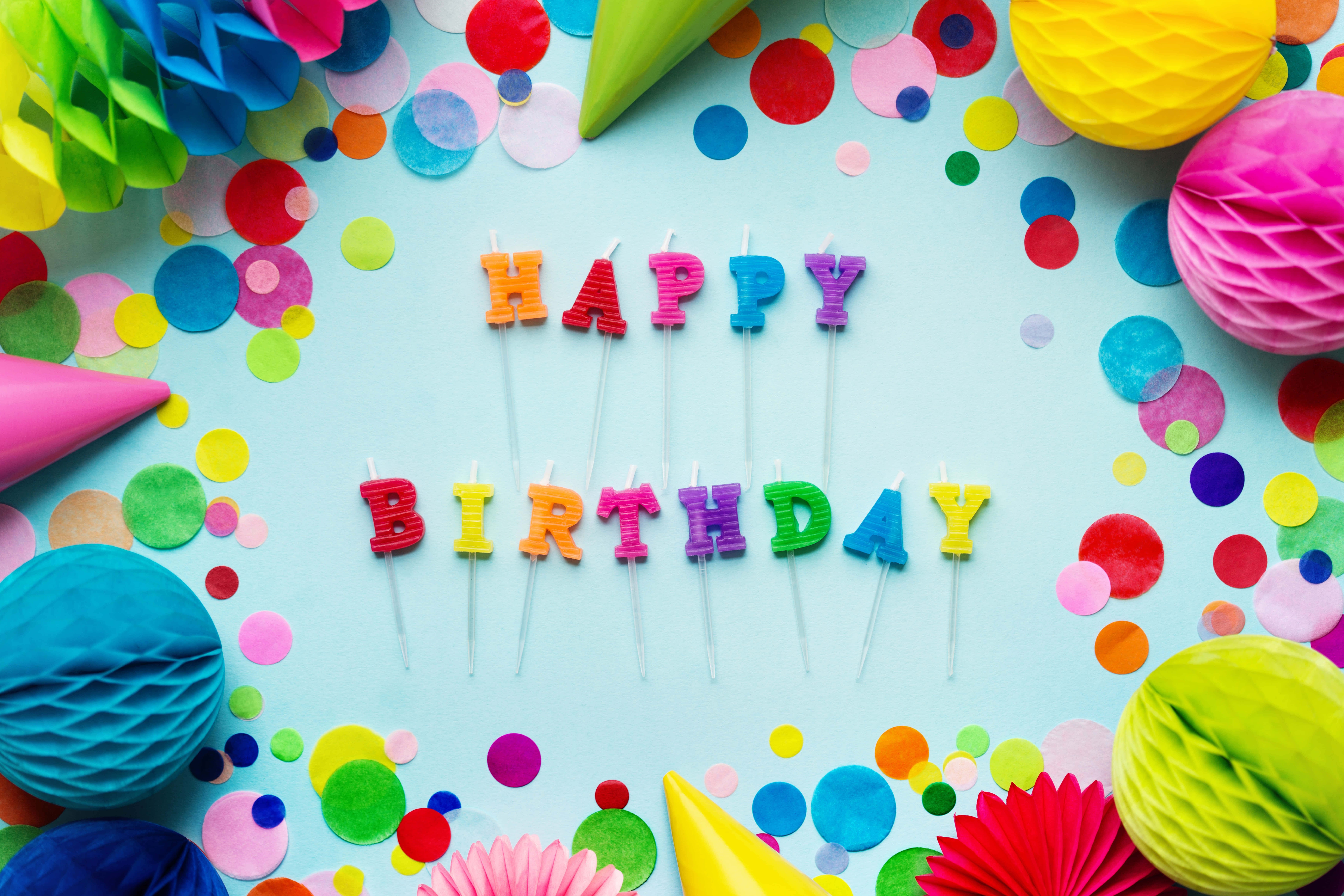生日快樂 桌布 壁紙 — 色彩繽紛的生日蠟燭拼出 happy birthday，周圍環繞著彩色紙屑和紙裝飾，背景為淺藍色。