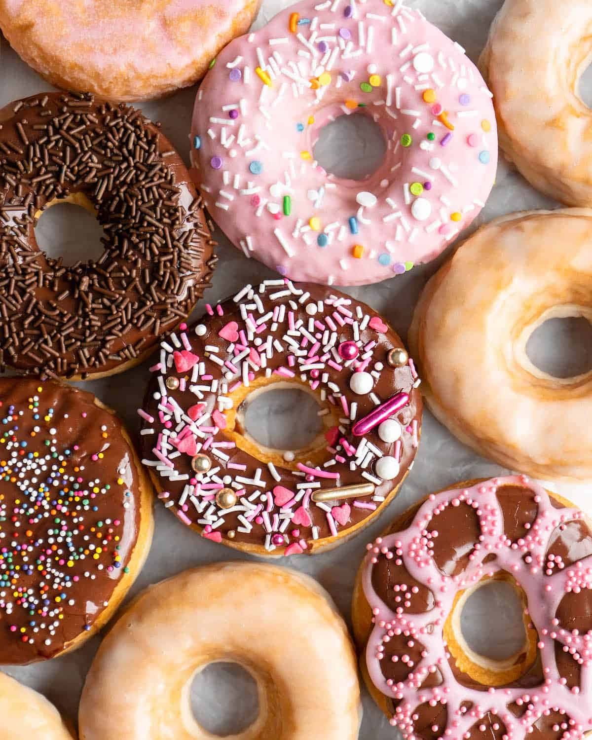 Glazed Donut 桌布 壁紙 — 色彩繽紛的糖霜和彩糖甜甜圈，以誘人的俯拍鏡頭排列。