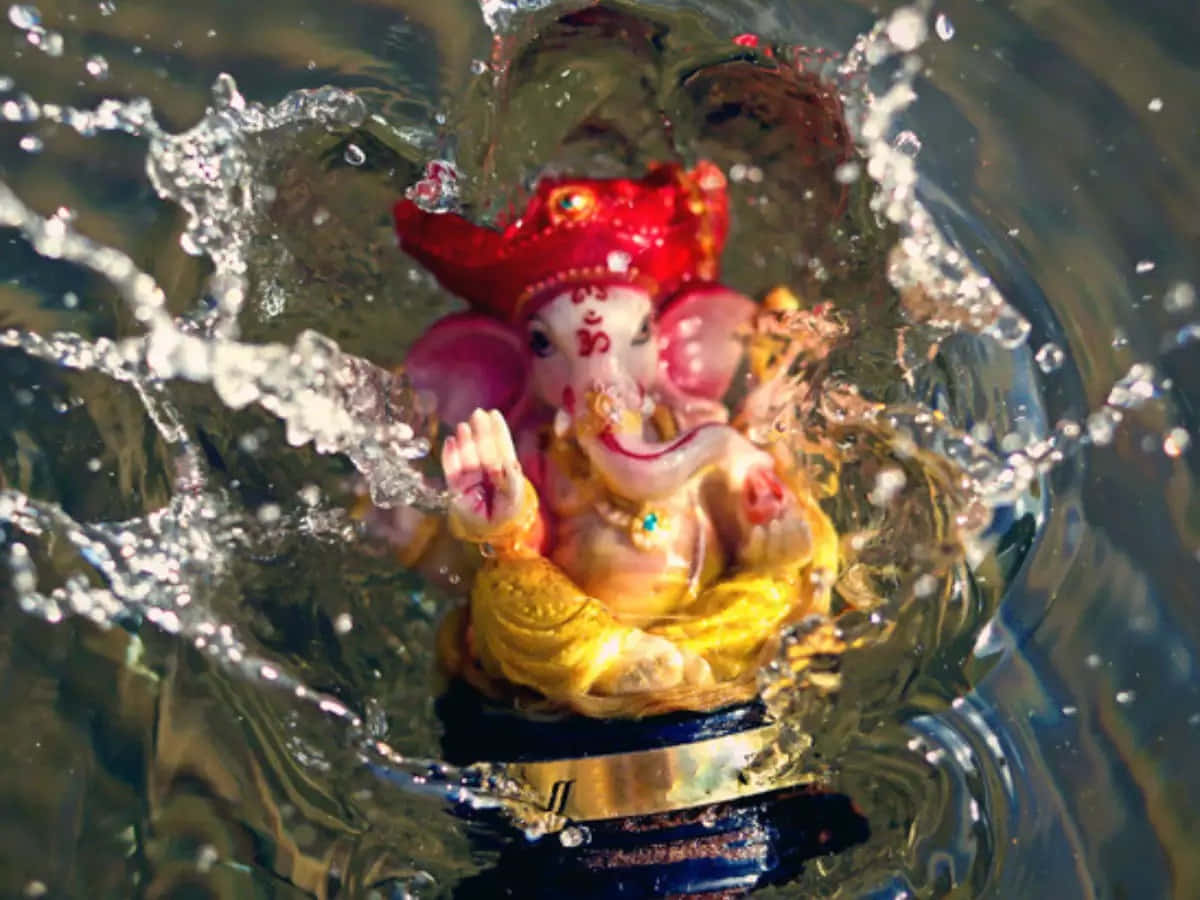 Ganesh Chaturthi 桌布 壁紙 — 色彩繽紛的象神雕像從濺起的水花中浮現，周圍環繞著動態的水滴。