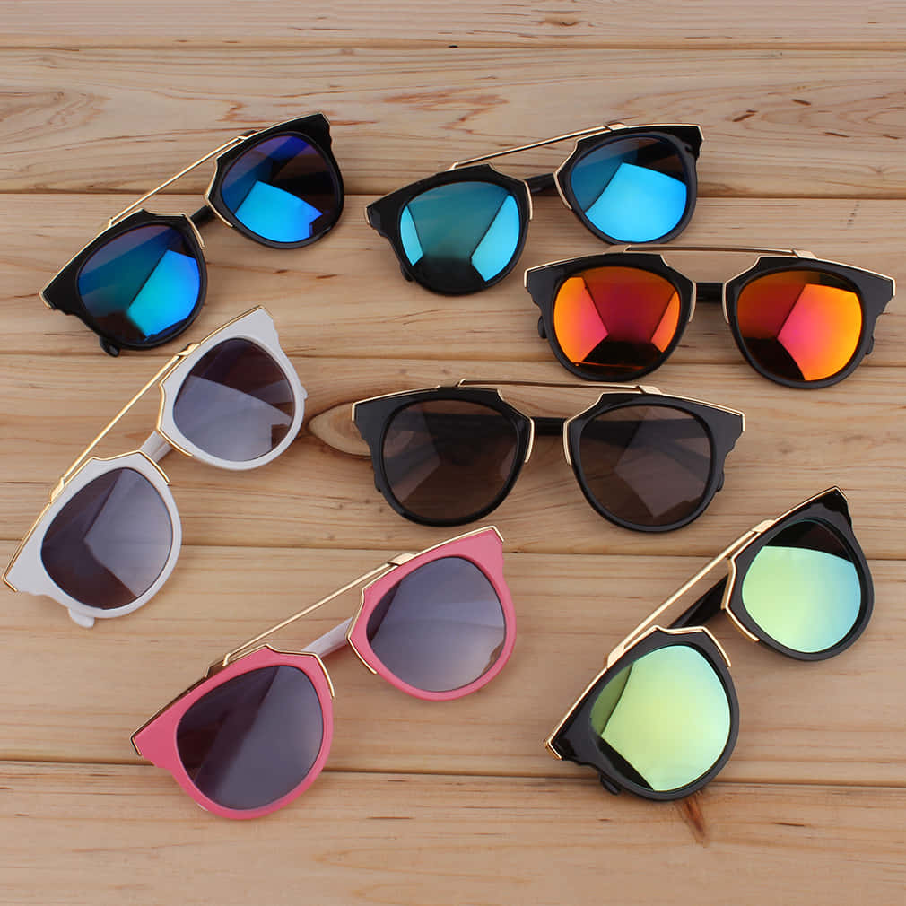 Sunglasses 桌布 壁紙 — 色彩繽紛的貓眼太陽眼鏡系列，配有反光鏡片，排列在淺色木質表面上。