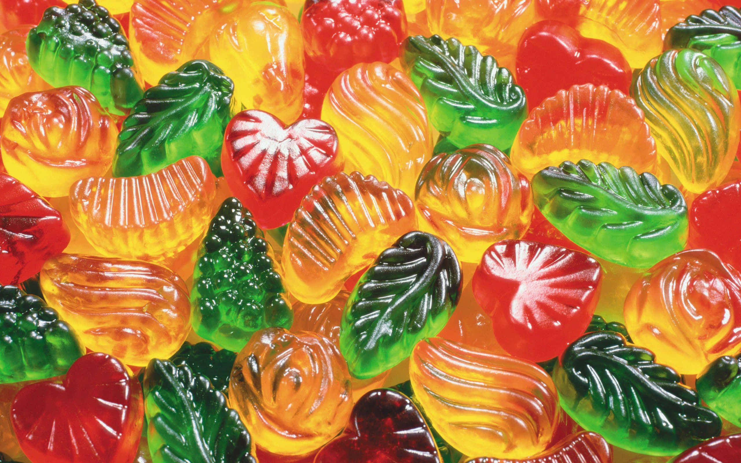 糖果 桌布 壁紙 — 色彩繽紛的軟糖特寫，形狀包括葉子、心形和花朵，具有光澤半透明的質感。
