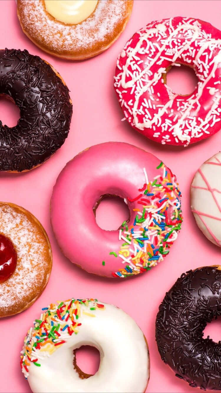 Cute Donut 桌布 壁紙 — 色彩繽紛的釉面和灑糖甜甜圈排列在充滿活力的粉紅色背景上。