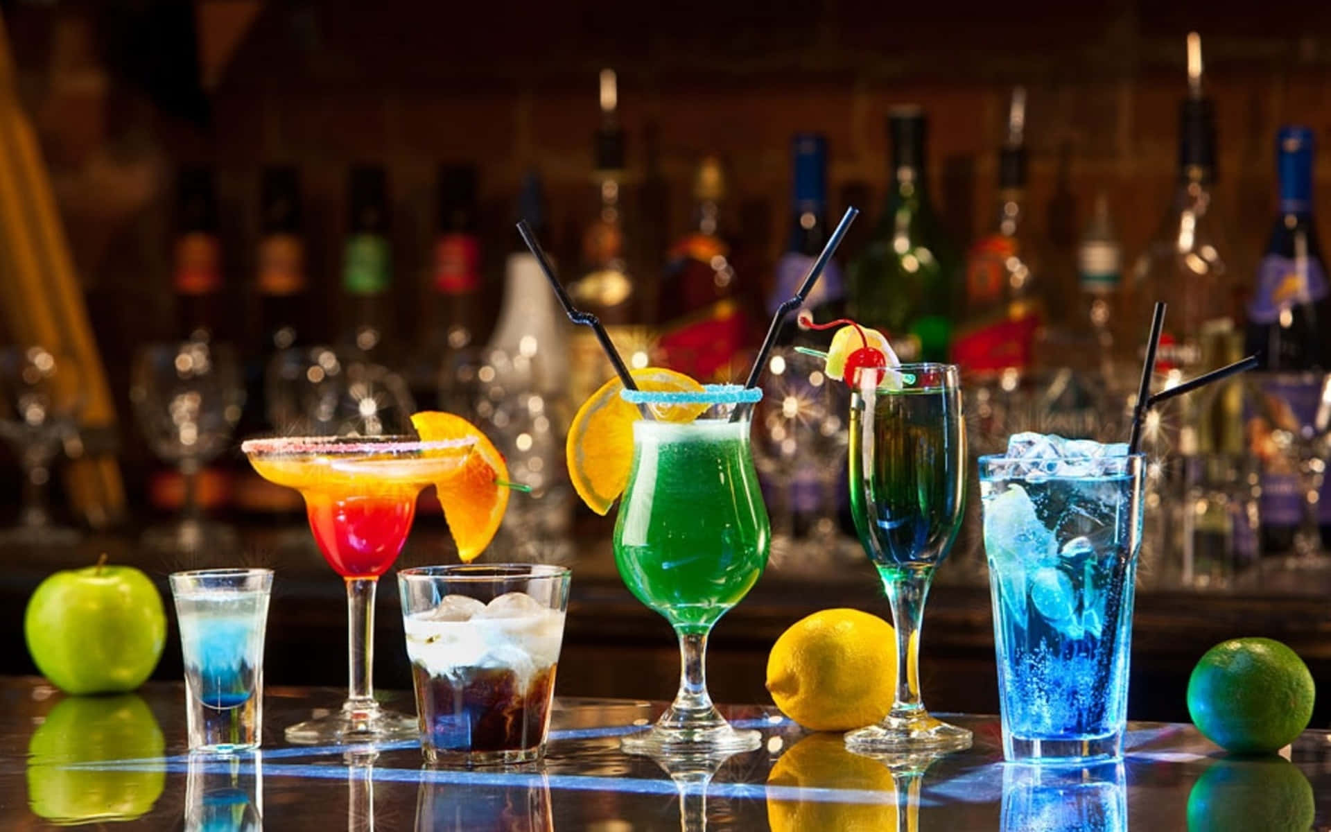 drinks 桌布 壁紙 — 色彩繽紛的雞尾酒放在彩色玻璃杯中，配上水果裝飾和冰塊，置於反射的吧檯上，背景有酒瓶。