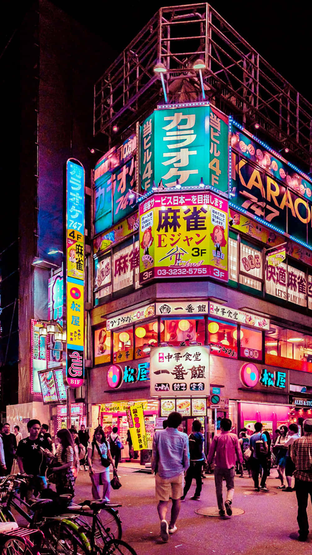 日本 桌布 壁紙 — 色彩繽紛的霓虹燈照亮了夜晚繁忙的東京街角，行人走過發光的卡拉OK和餐廳廣告。