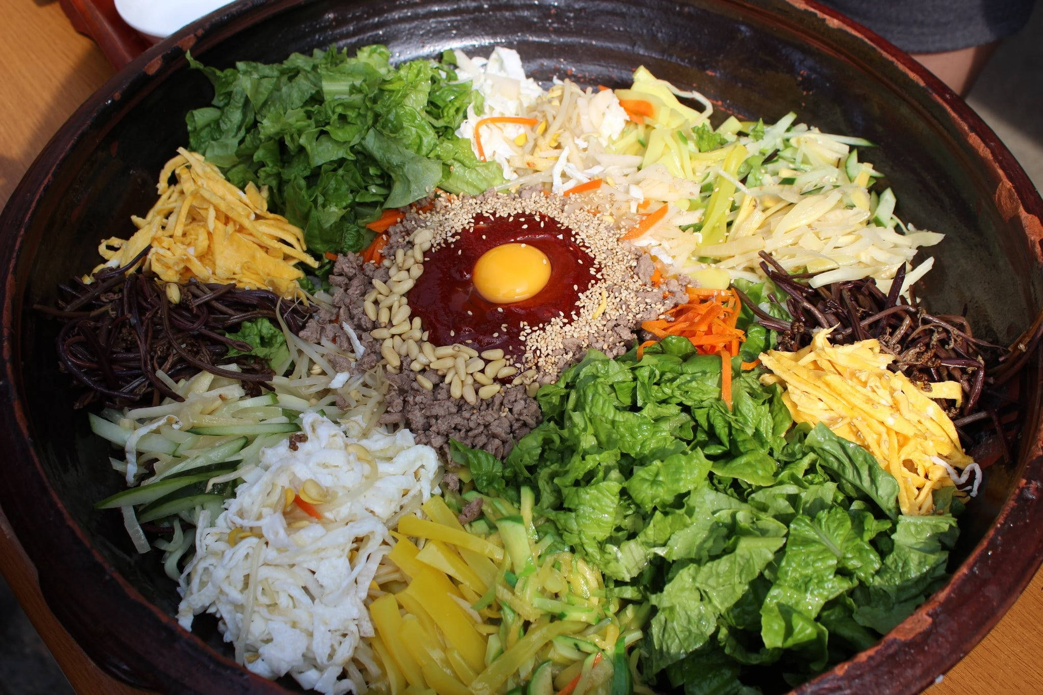 烹飪 桌布 壁紙 — 色彩繽紛的韓式石鍋拌飯，上面放有生蛋黃和芝麻。