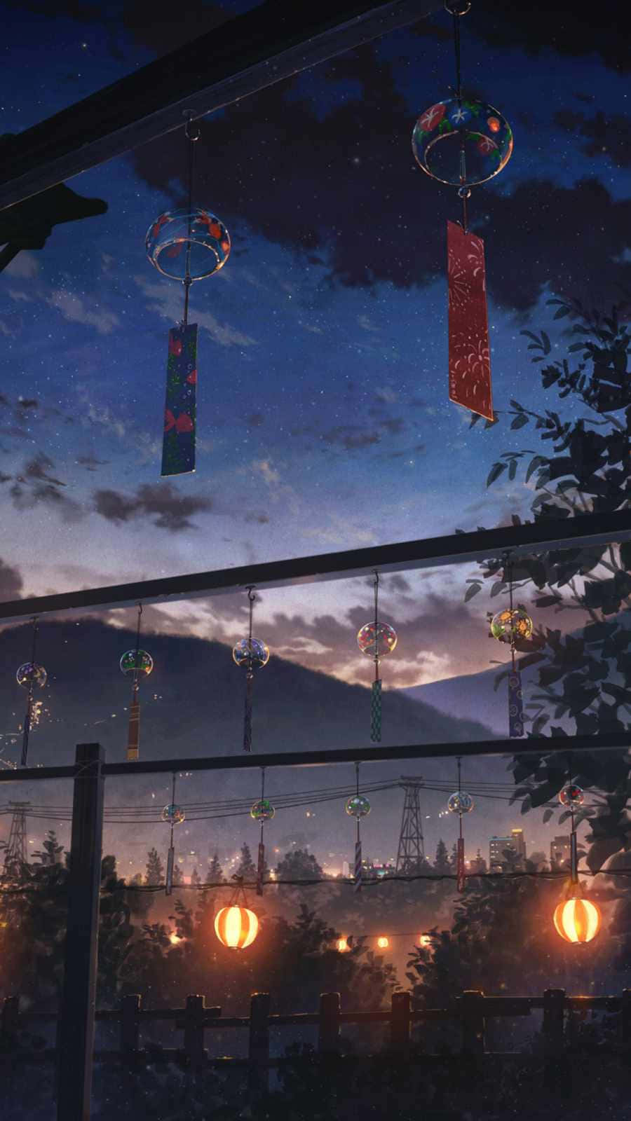 手機 桌布 壁紙 — 色彩繽紛的風鈴掛在繁星點點的暮色天空下，下方是發光的城市景觀和遠山。