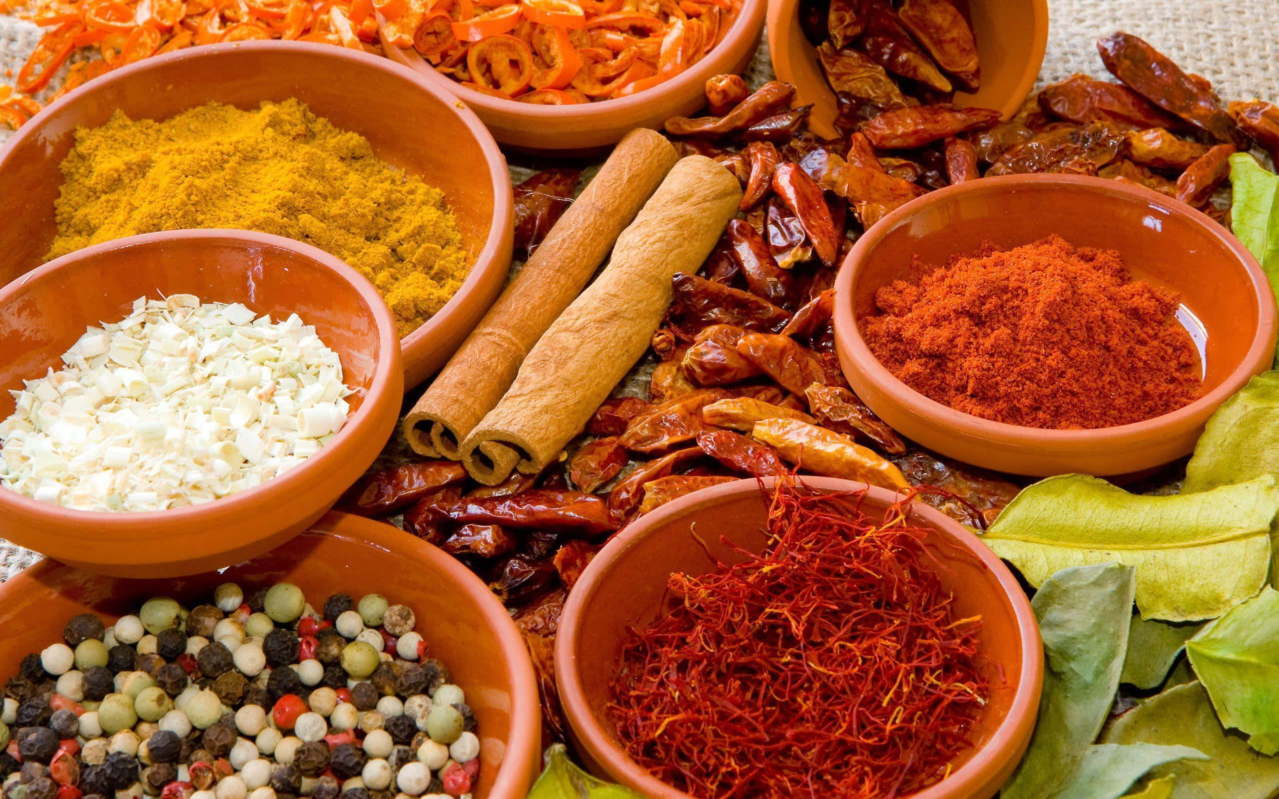 Spices 桌布 壁紙 — 色彩繽紛的香料和香草放在赤陶碗中，排列在帶紋理的表面上。