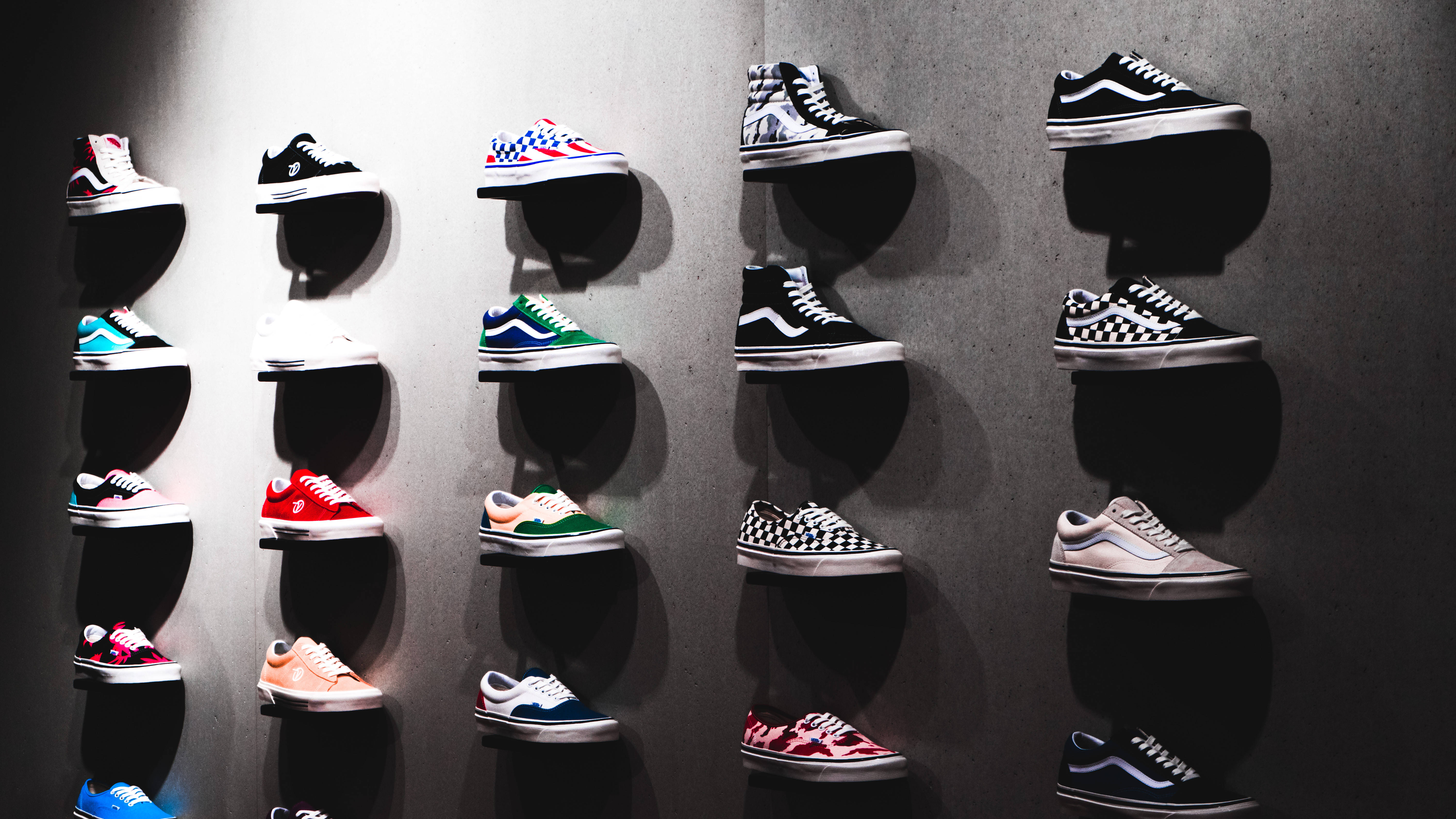Vans 桌布 壁紙 — 色彩鮮豔的Vans運動鞋展示在浮動層架上，背景為紋理灰色牆壁，搭配戲劇性聚光燈。