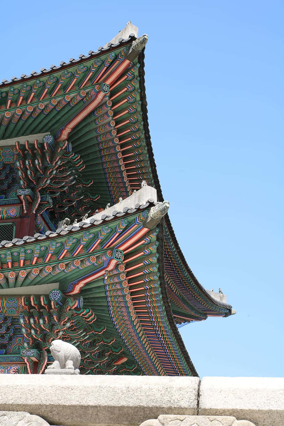 Architecture 桌布 壁紙 — 色彩鮮豔的傳統韓國寺廟屋頂，帶有複雜圖案和石獅雕像，映襯著清澈的藍天。