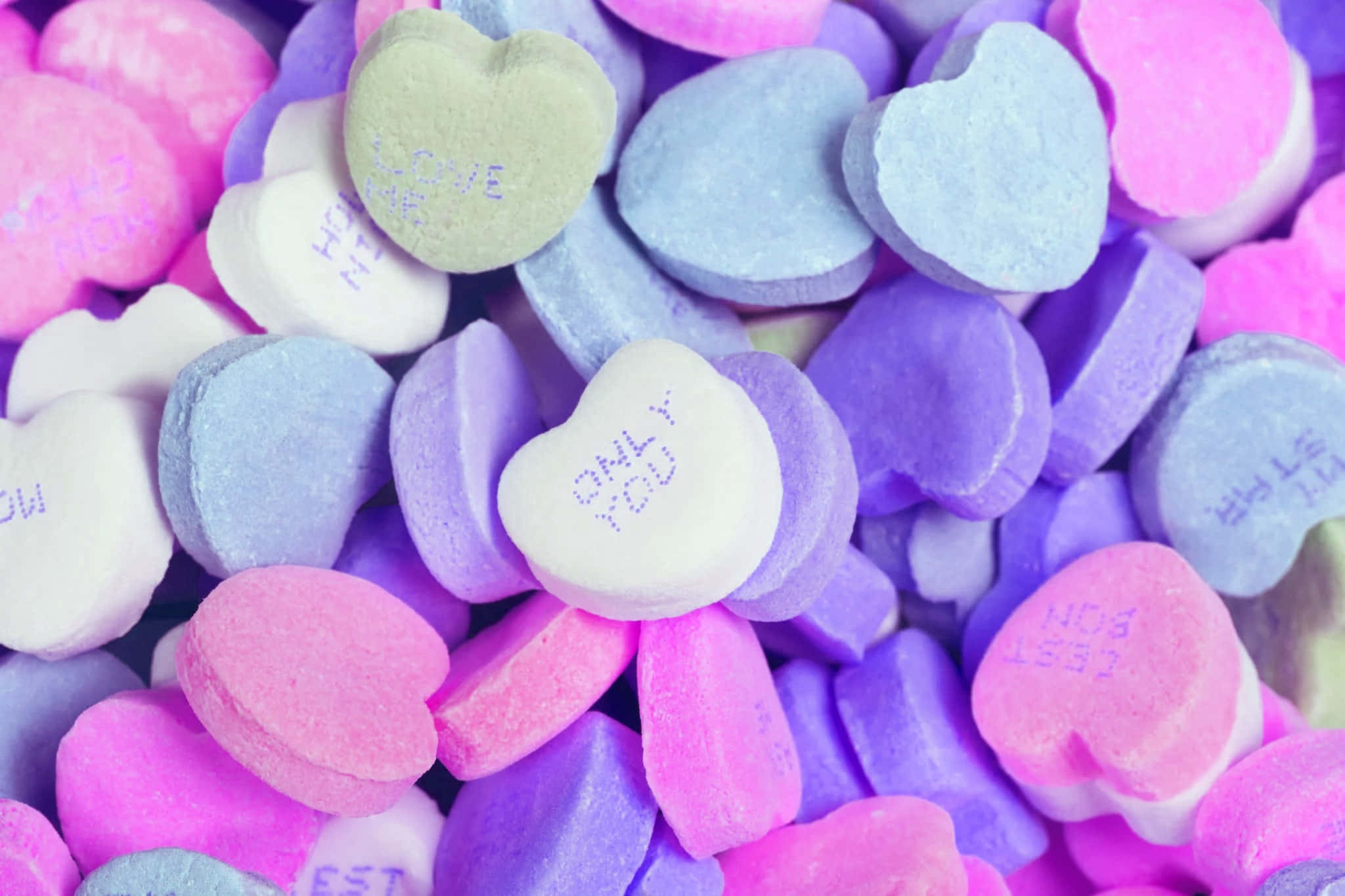 愛心 桌布 壁紙 — 色彩鮮豔的心形糖果特寫，上面有「ONLY YOU」和「LOVE」等訊息，採用粉紅、紫和藍色調的柔和色彩。