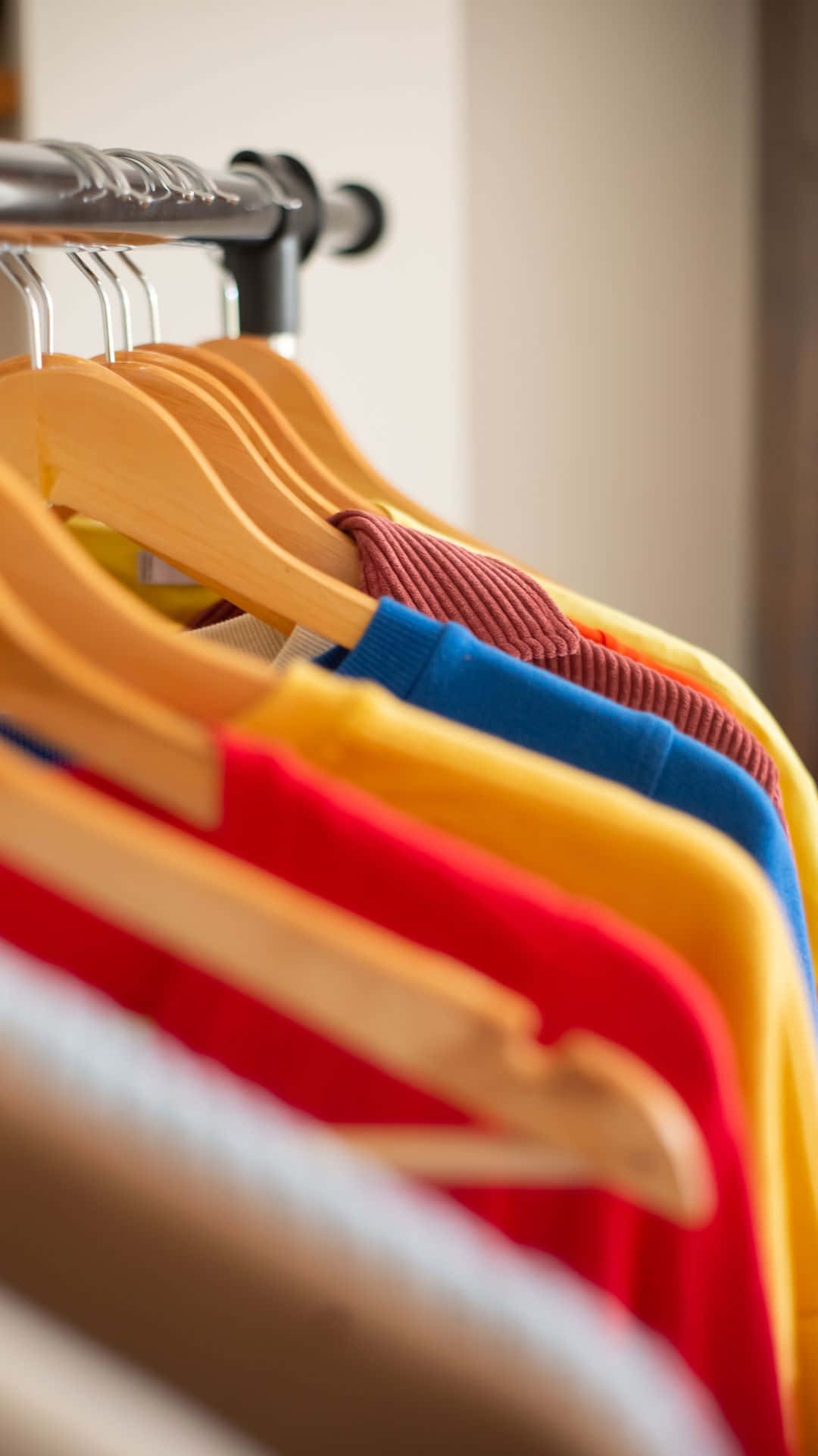 Clothes 桌布 壁紙 — 色彩鮮豔的襯衫整齊地掛在木衣架上，置於柔和燈光的衣櫃中，營造出歡樂有序的展示效果。