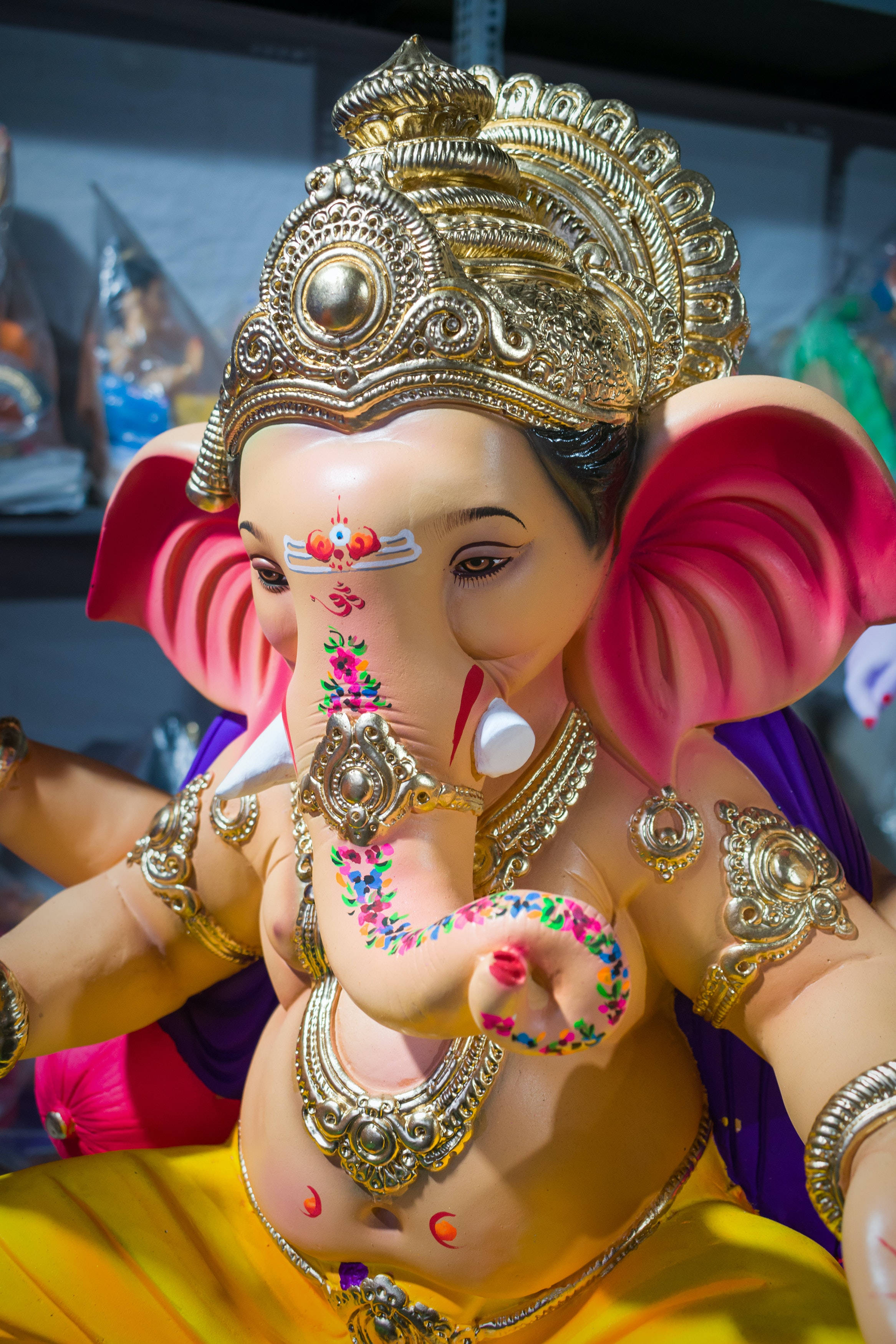 ganesh iPhone 桌布 壁紙 — 色彩鮮豔的象頭神像，以金飾和花卉圖案裝飾其象鼻和前額。