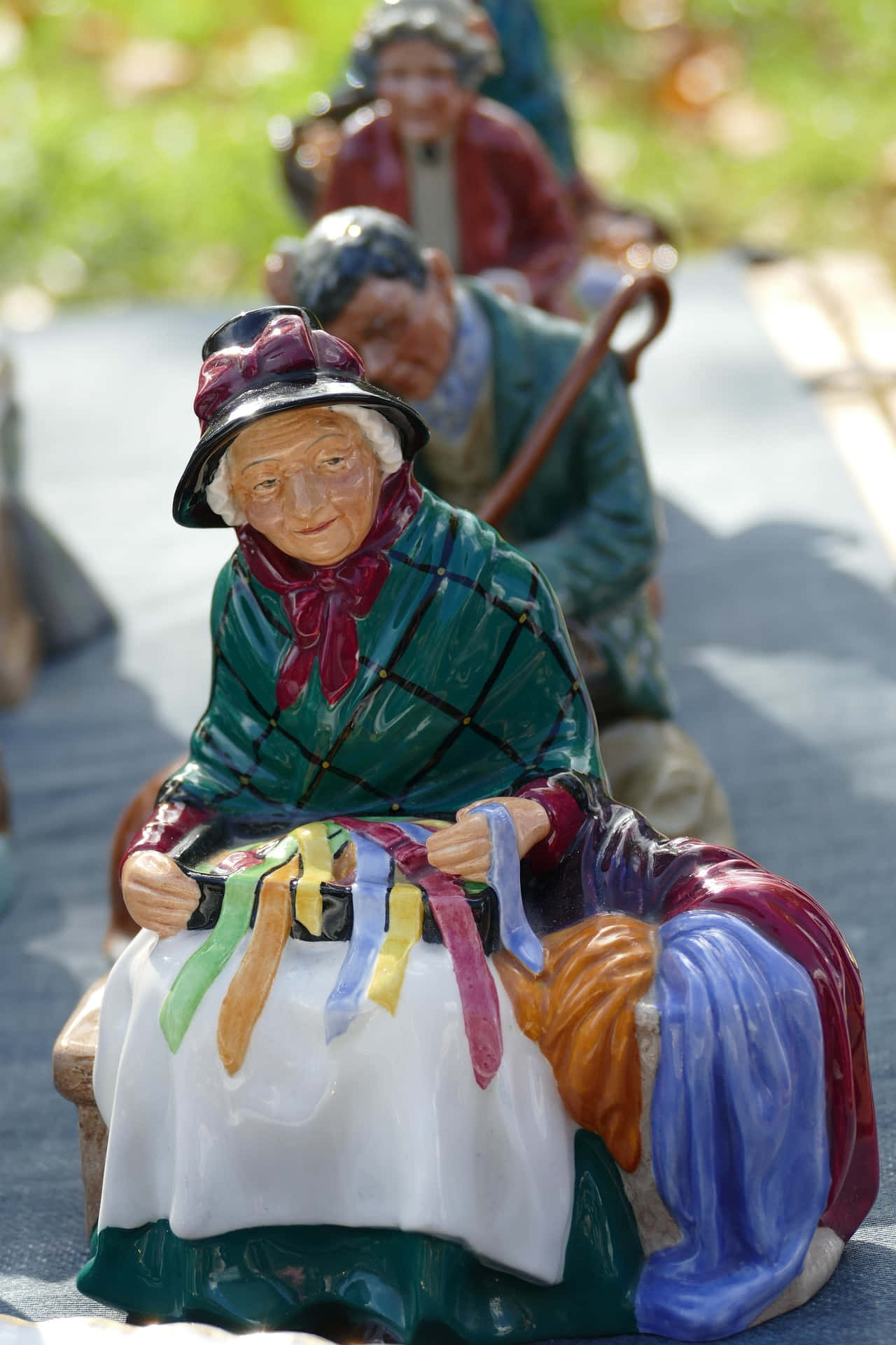 figure 桌布 壁紙 — 色彩鮮豔的陶瓷老婦編織公仔在明亮的陽光下排成一排坐在戶外。