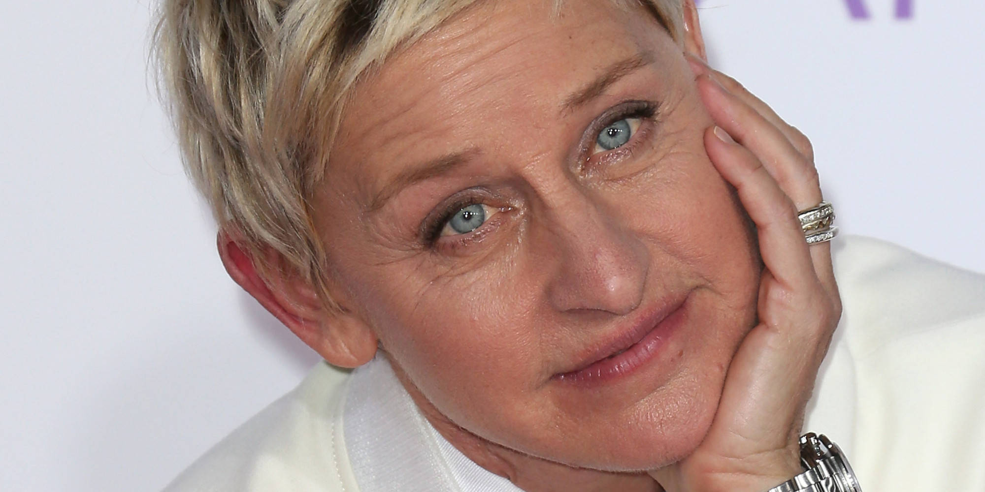 Ellen Degeneres 桌布 壁紙 — 艾倫·狄珍妮絲將手放在臉頰上，在純白背景前溫柔微笑。
