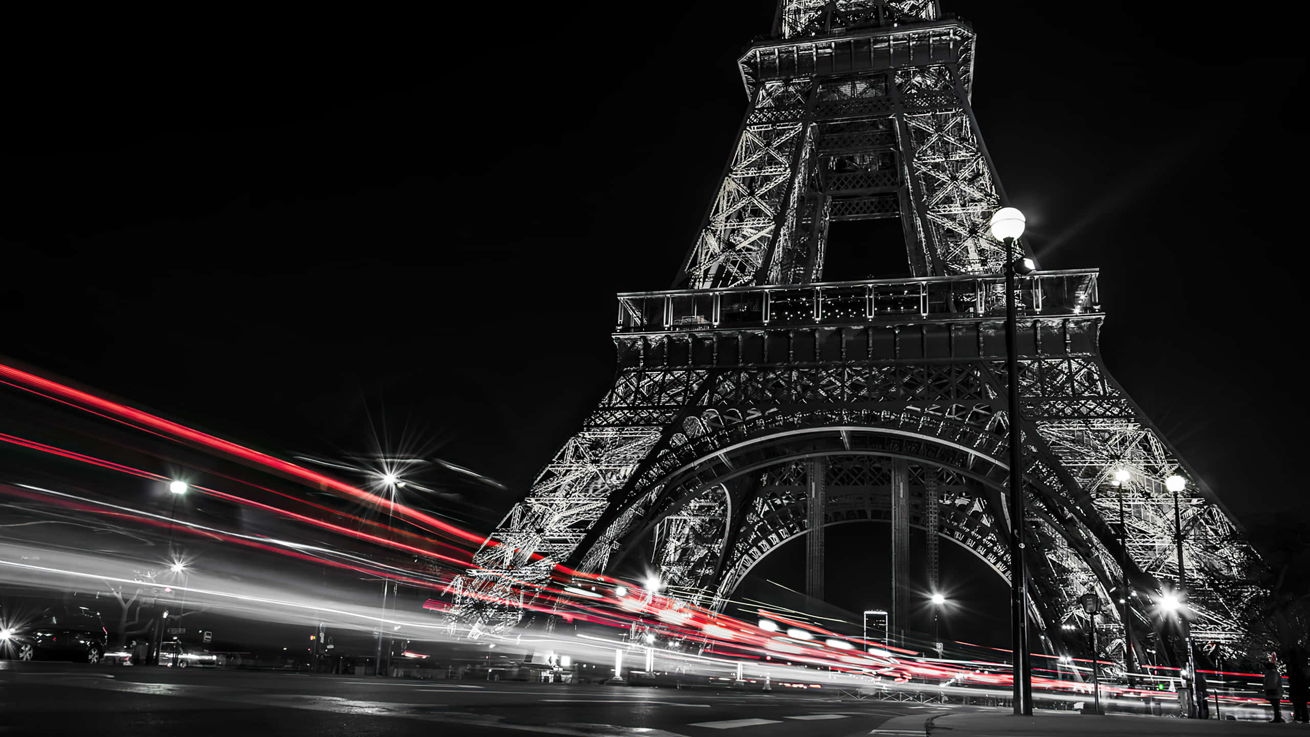 Eiffel Tower 桌布 壁紙 — 艾菲爾鐵塔以單色調高聳入夜空，鮮豔的紅色光軌疾馳而過。