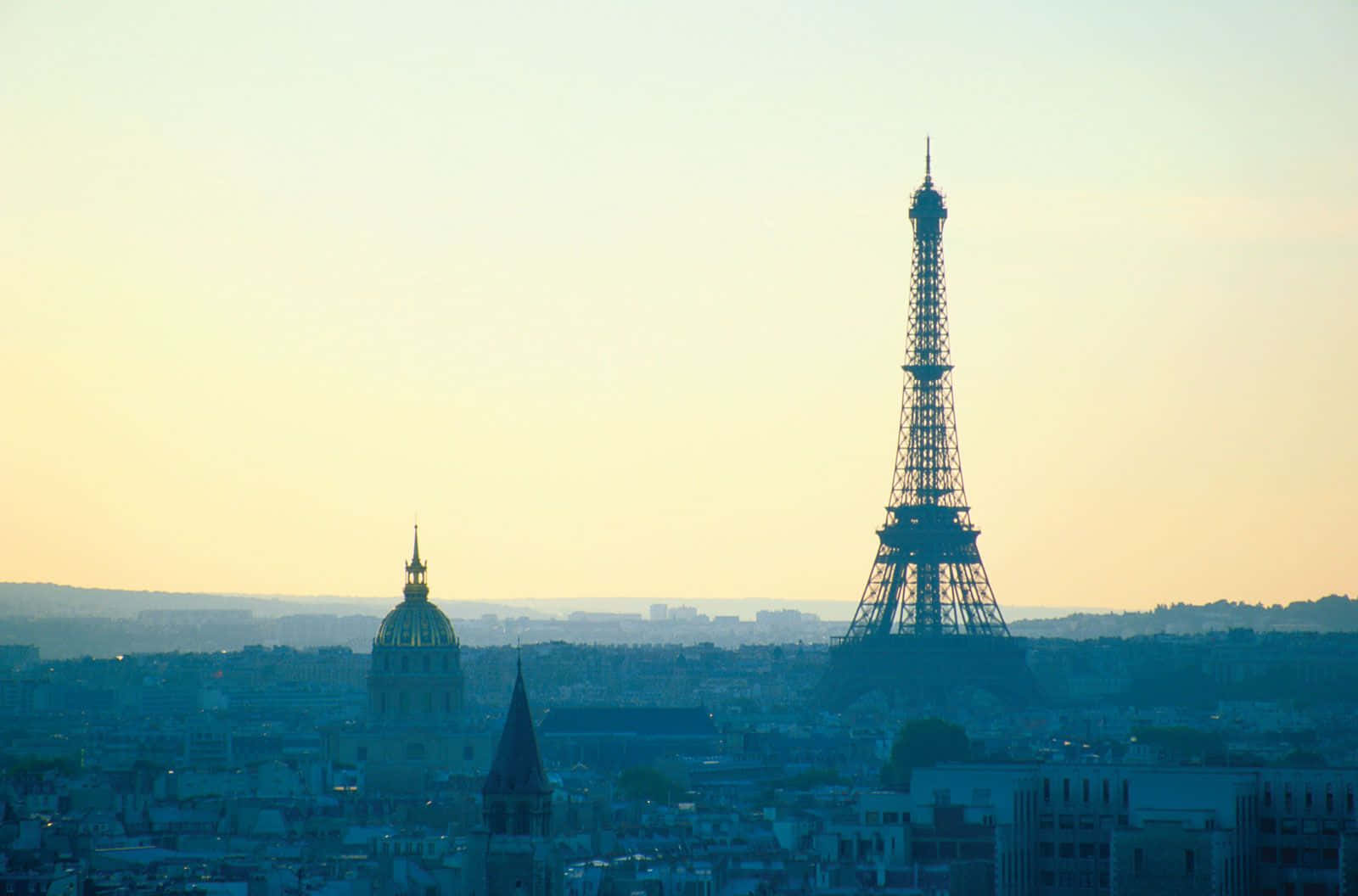 french 桌布 壁紙 — 艾菲爾鐵塔和圓頂在巴黎屋頂上朦朧的金色日落中形成剪影。
