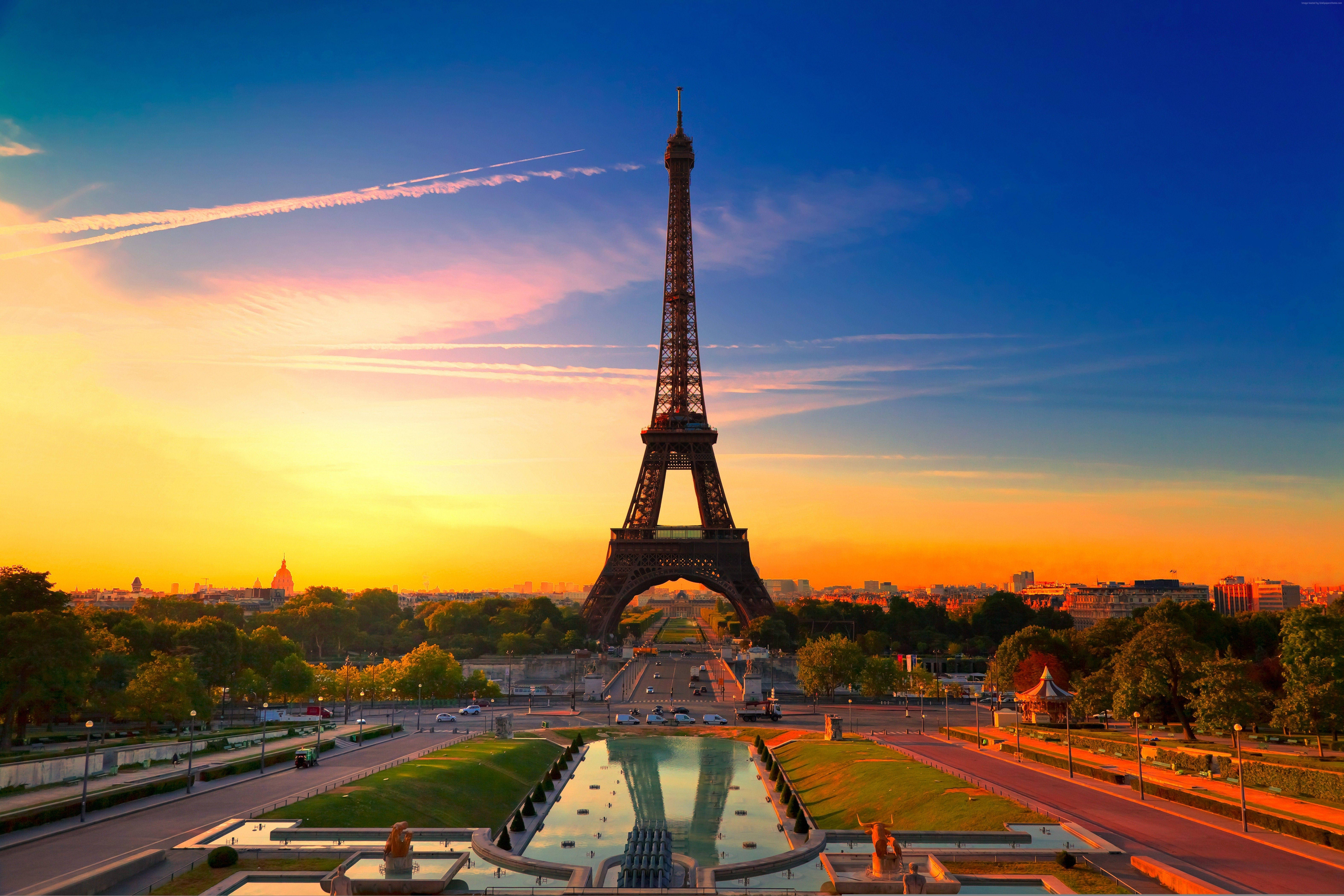 Paris Eiffel Tower 桌布 壁紙 — 艾菲爾鐵塔在充滿活力的日落天空下高聳，金色光線反射在下方長長的水景上。