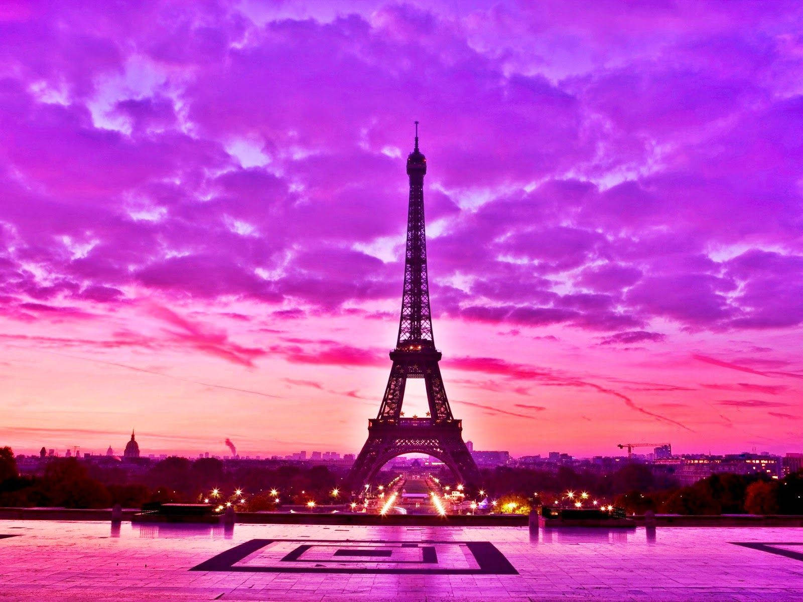 Eiffel Tower 桌布 壁紙 — 艾菲爾鐵塔在充滿活力的紫色和粉紅色日落天空的襯托下呈現剪影，下方城市燈光閃爍。