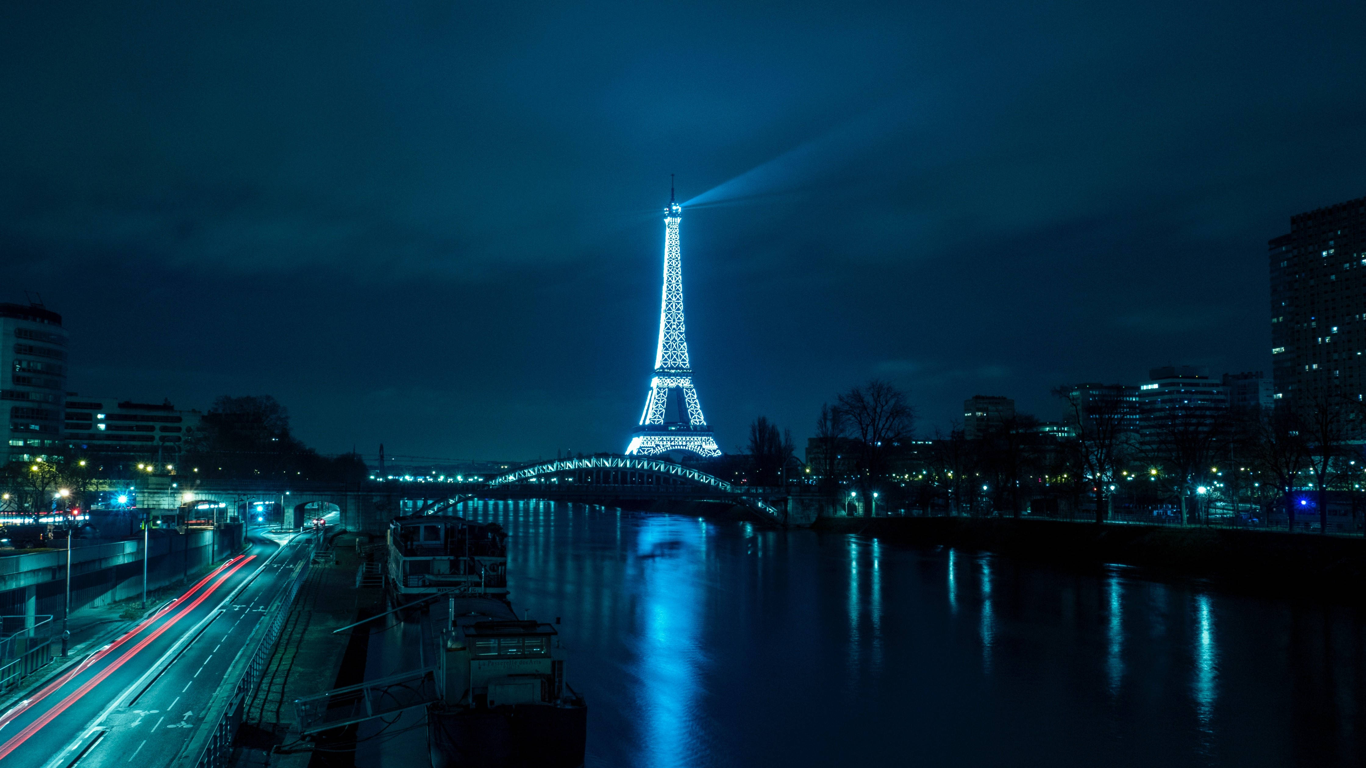 France 桌布 壁紙 — 艾菲爾鐵塔在夜晚閃耀光芒，將光束投射到塞納河上，交通燈的條紋反射在水面上。