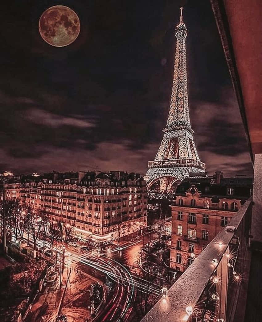 玫瑰金 桌布 壁紙 — 艾菲爾鐵塔在巨大紅色月亮下照亮的壯麗夜景，下方有條紋狀的城市燈光。