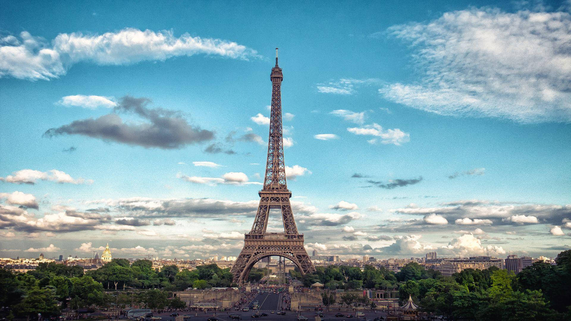 Eiffel Tower 桌布 壁紙 — 艾菲爾鐵塔在巴黎上空點綴著蓬鬆白雲的鮮豔藍天下高聳入雲。