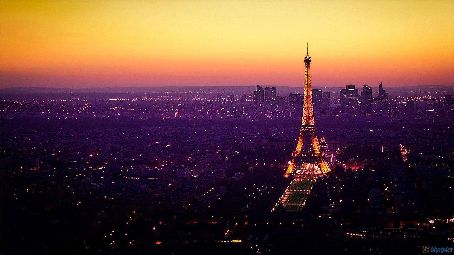 Eiffel Tower 桌布 壁紙 — 艾菲爾鐵塔在巴黎天際線上，映襯著火紅橙紫的日落，閃耀金光。