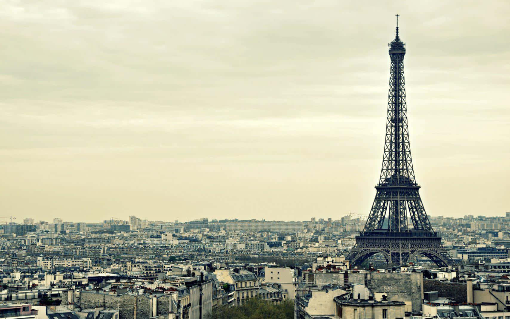 Paris Desktop 桌布 壁紙 — 艾菲爾鐵塔在巴黎屋頂上方升起，在柔和的陰天天空下呈現復古棕褐色調。