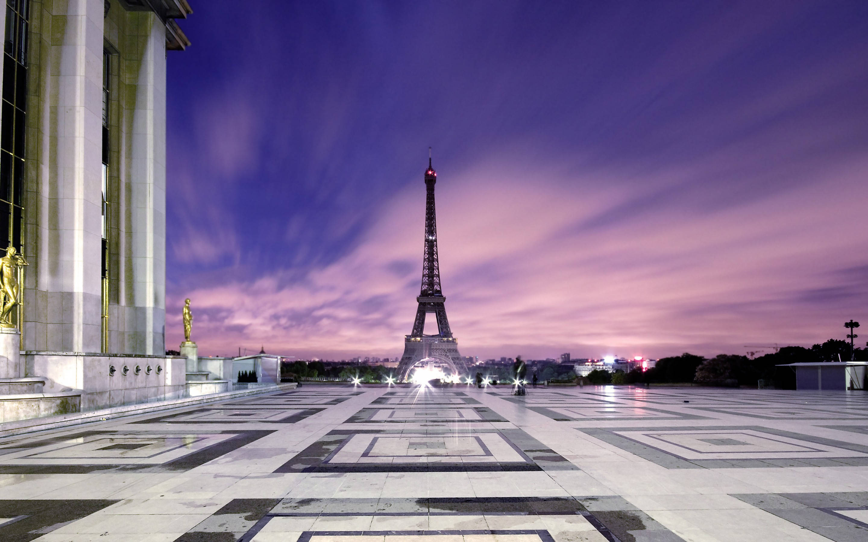 France 桌布 壁紙 — 艾菲爾鐵塔在幾何圖案廣場上，映襯著充滿活力的紫色和粉紅色暮色天空，閃耀著光芒。