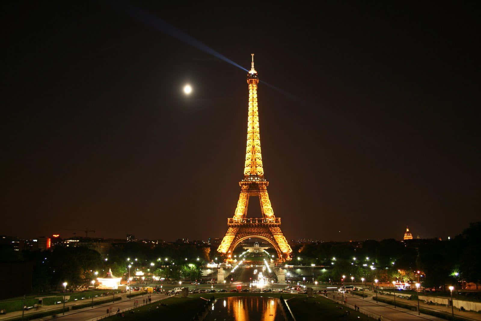 Eiffel Tower 桌布 壁紙 — 艾菲爾鐵塔在明亮的月光下溫暖地發光，雷射光束射向夜空。